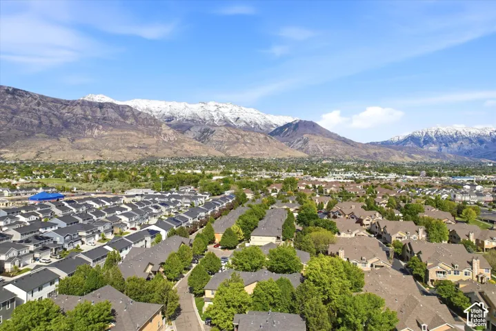 Expansive residential neighborhood featuring diverse housing styles, mature trees, and mountainous terrain with snow-capped peaks in the distance