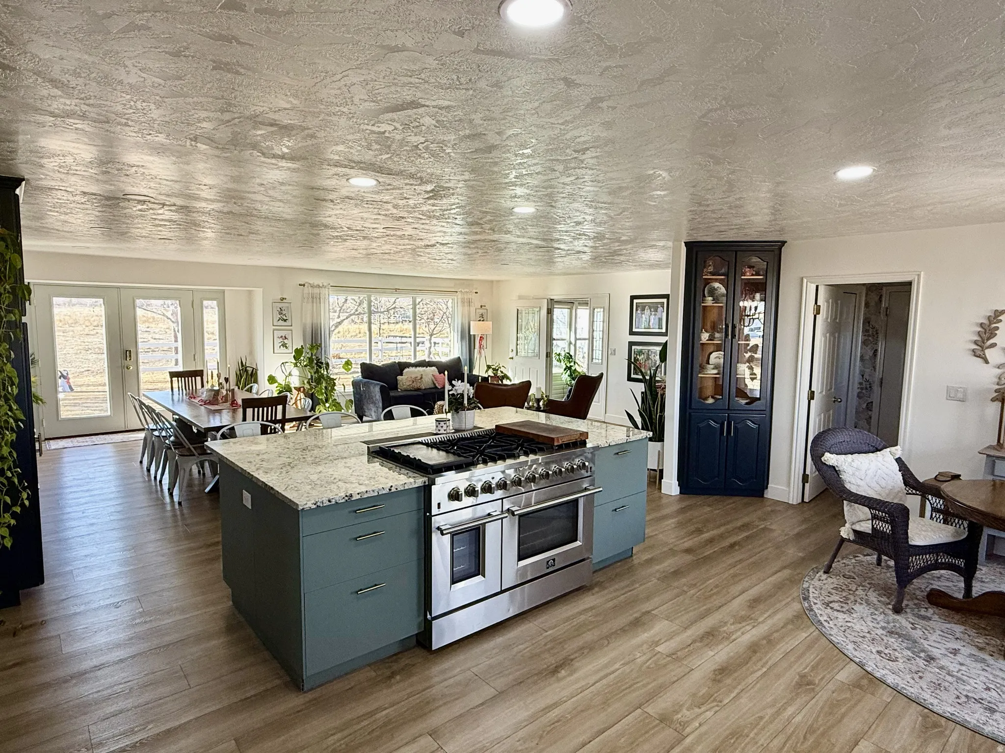 Kitchen island featuring a built-in stainless steel range, light-toned countertop, and blue-green cabinetry