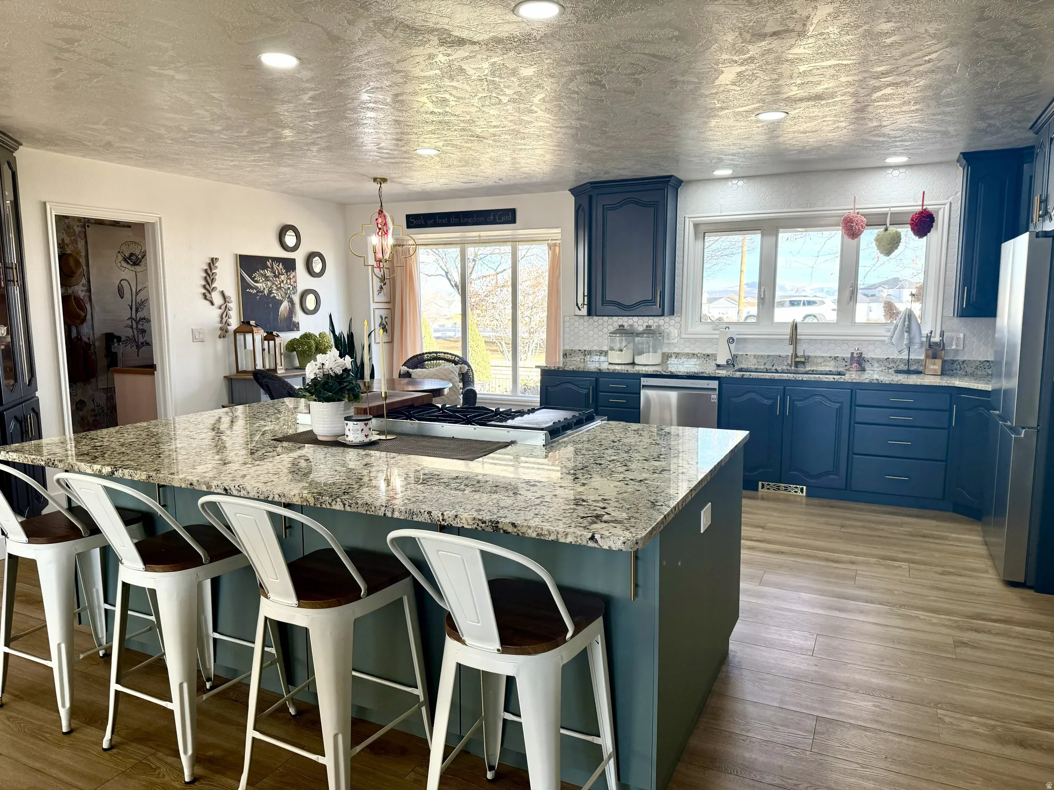 Spacious kitchen featuring a large island with granite countertops, a built-in cooktop, and seating
