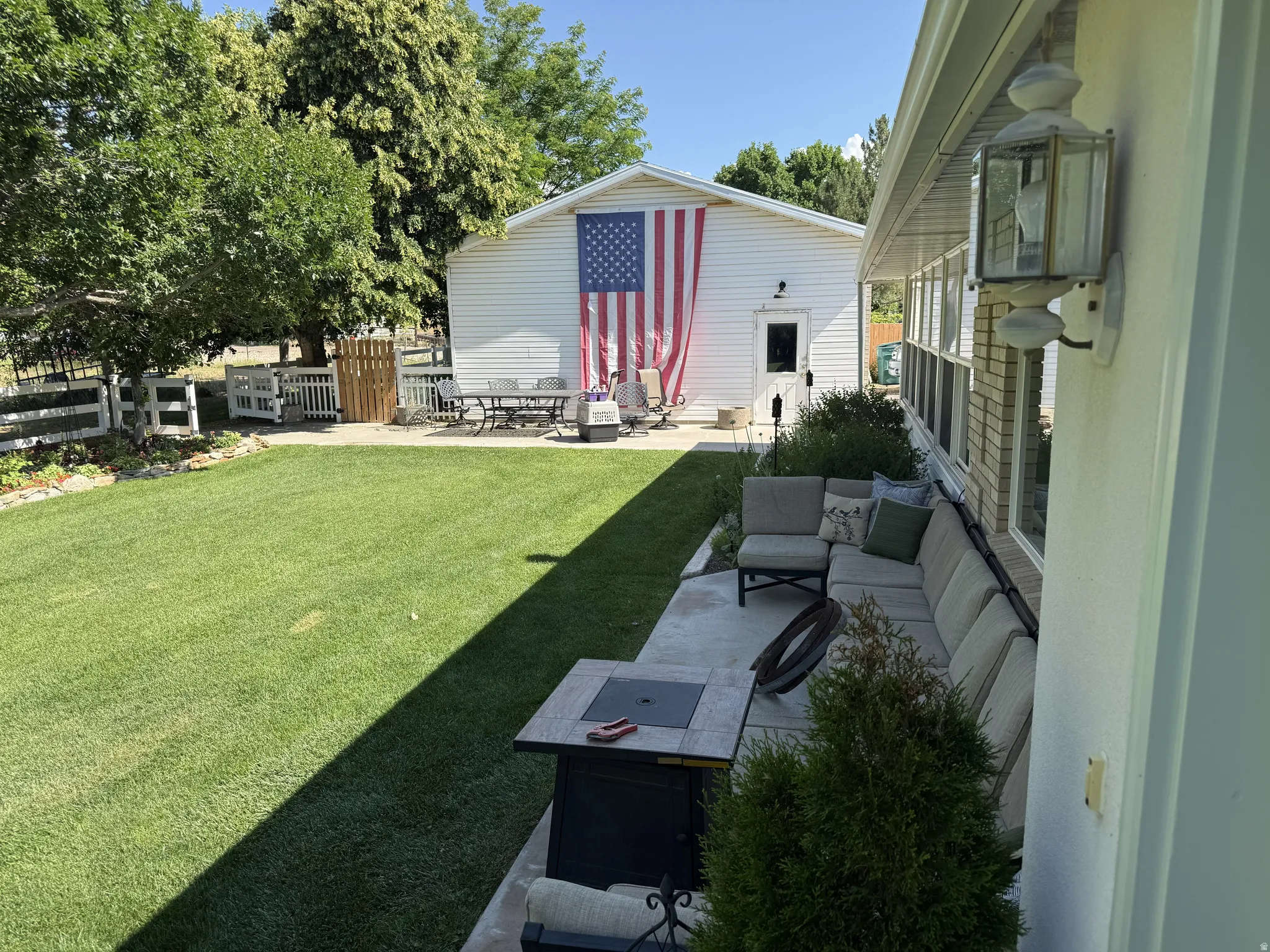 Expansive rear yard featuring a concrete patio, a built-in fire pit, and a segmented outdoor sectional