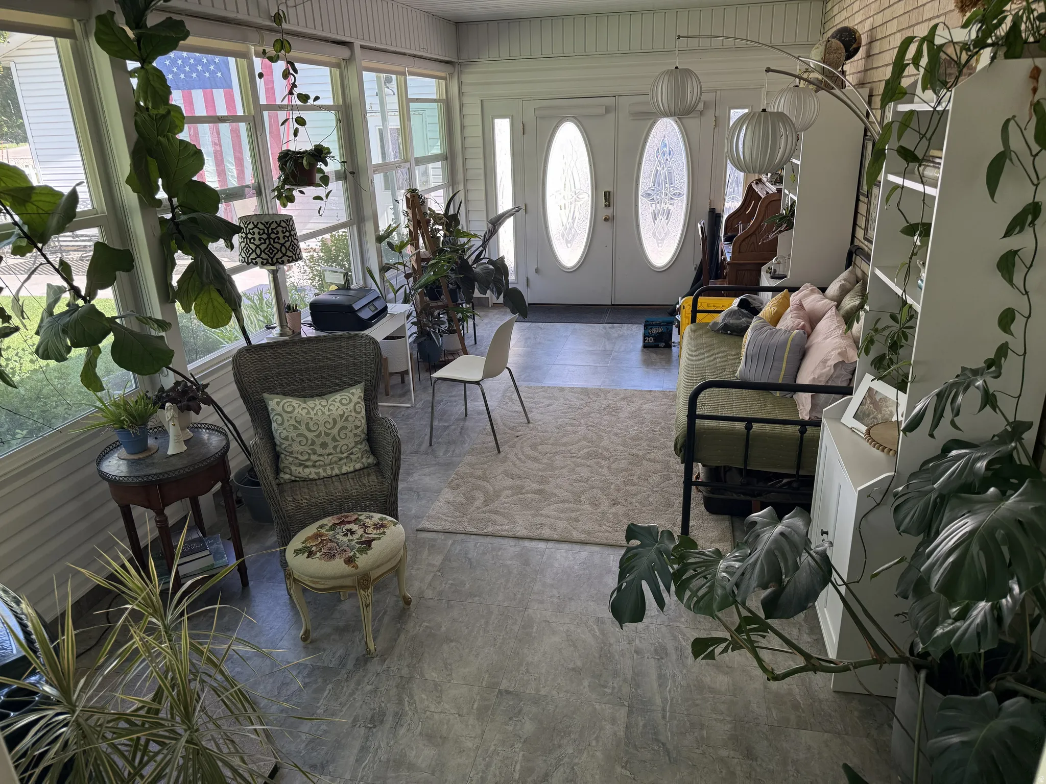 Sunroom featuring extensive window-lined walls, double entry doors with decorative glass inserts, and durable tile flooring