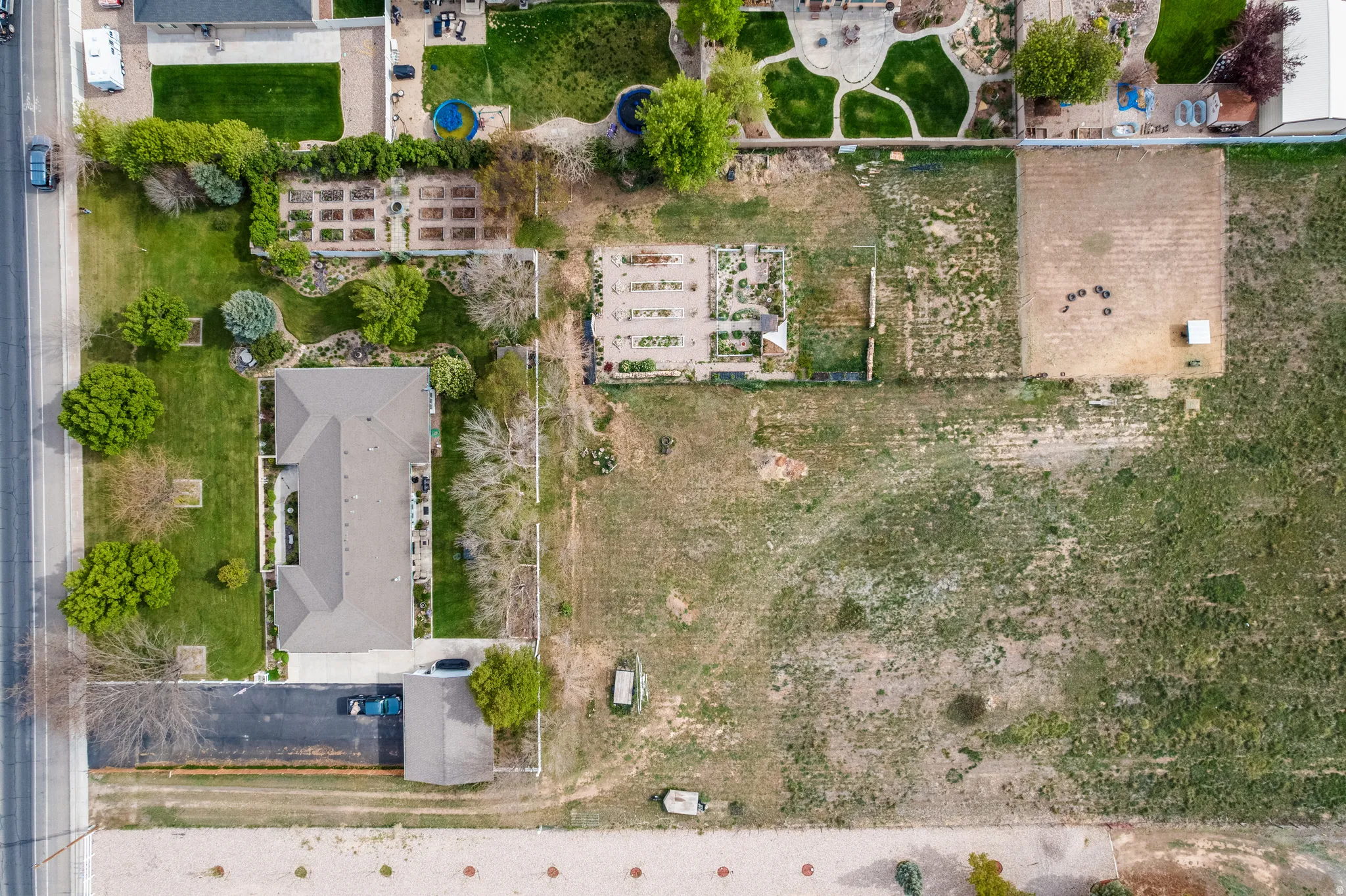 Expansive property featuring a large residential structure with an attached garage, substantial paved parking area, and a significant undeveloped land parcel