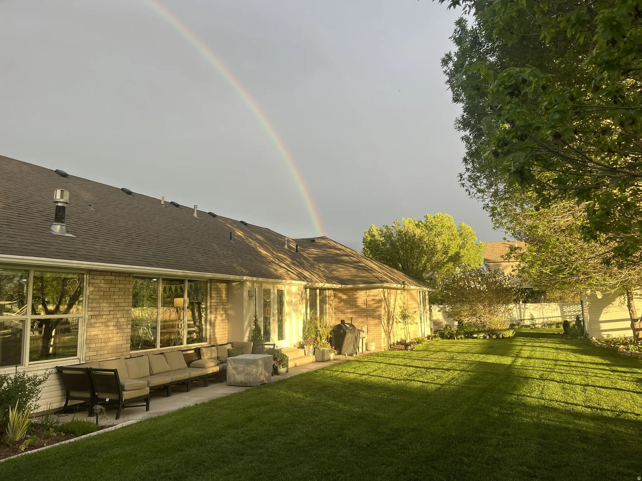 Expansive backyard featuring a manicured lawn, a paved patio, and mature trees