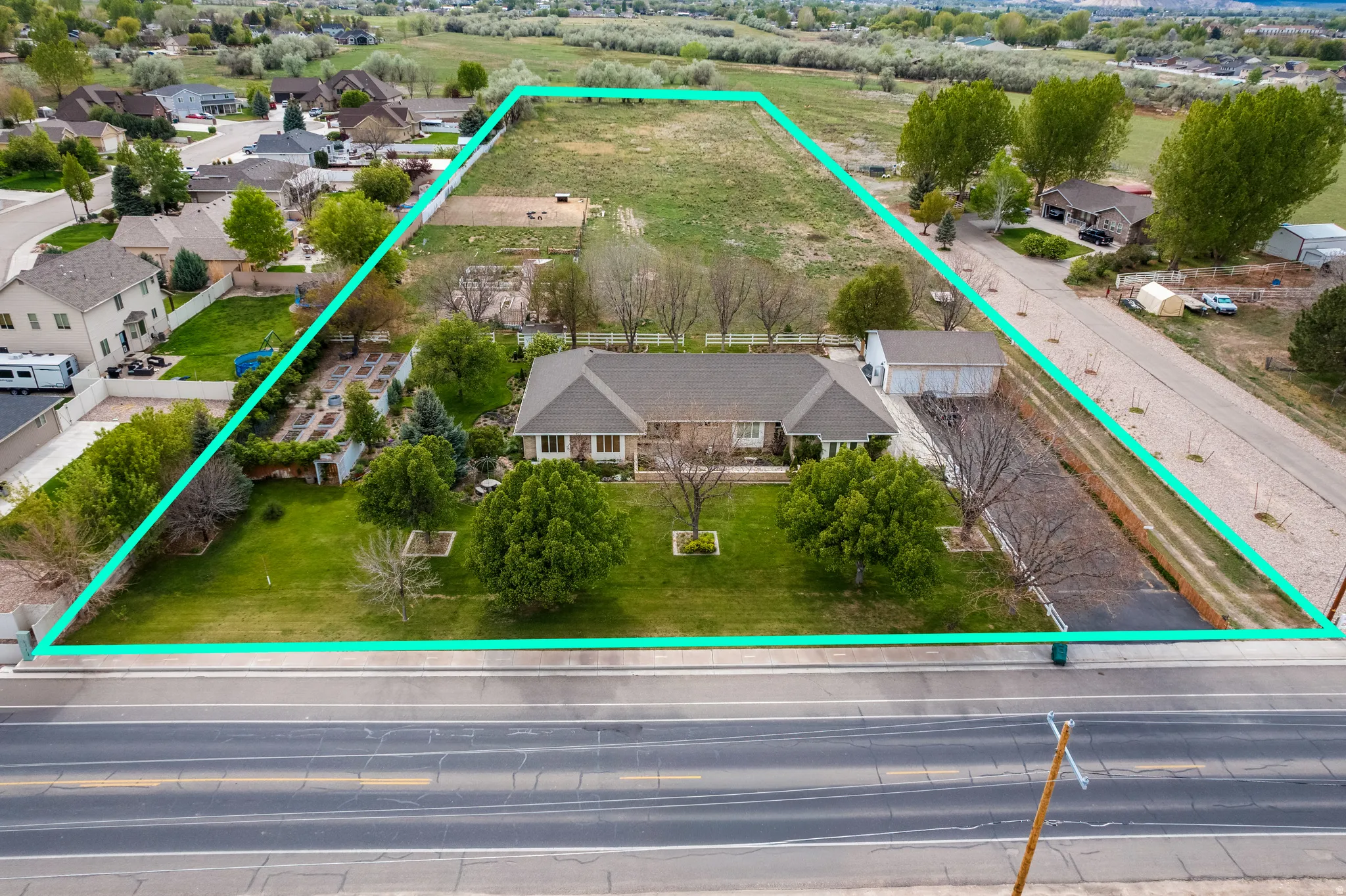 Expansive property featuring a single-story residence, detached garage, substantial undeveloped land, mature landscaping, and road frontage