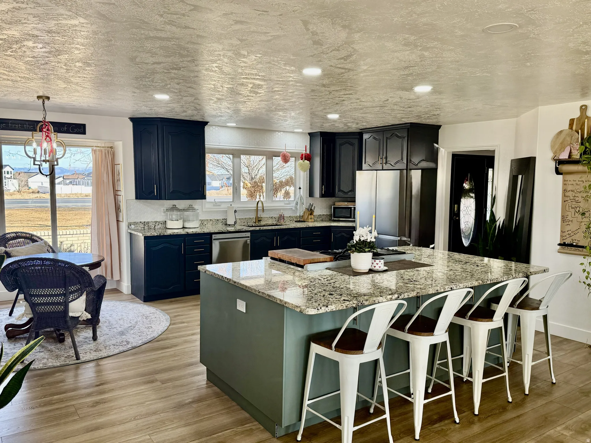 Spacious kitchen featuring an expansive center island with seating, granite countertops, and wood-finish flooring