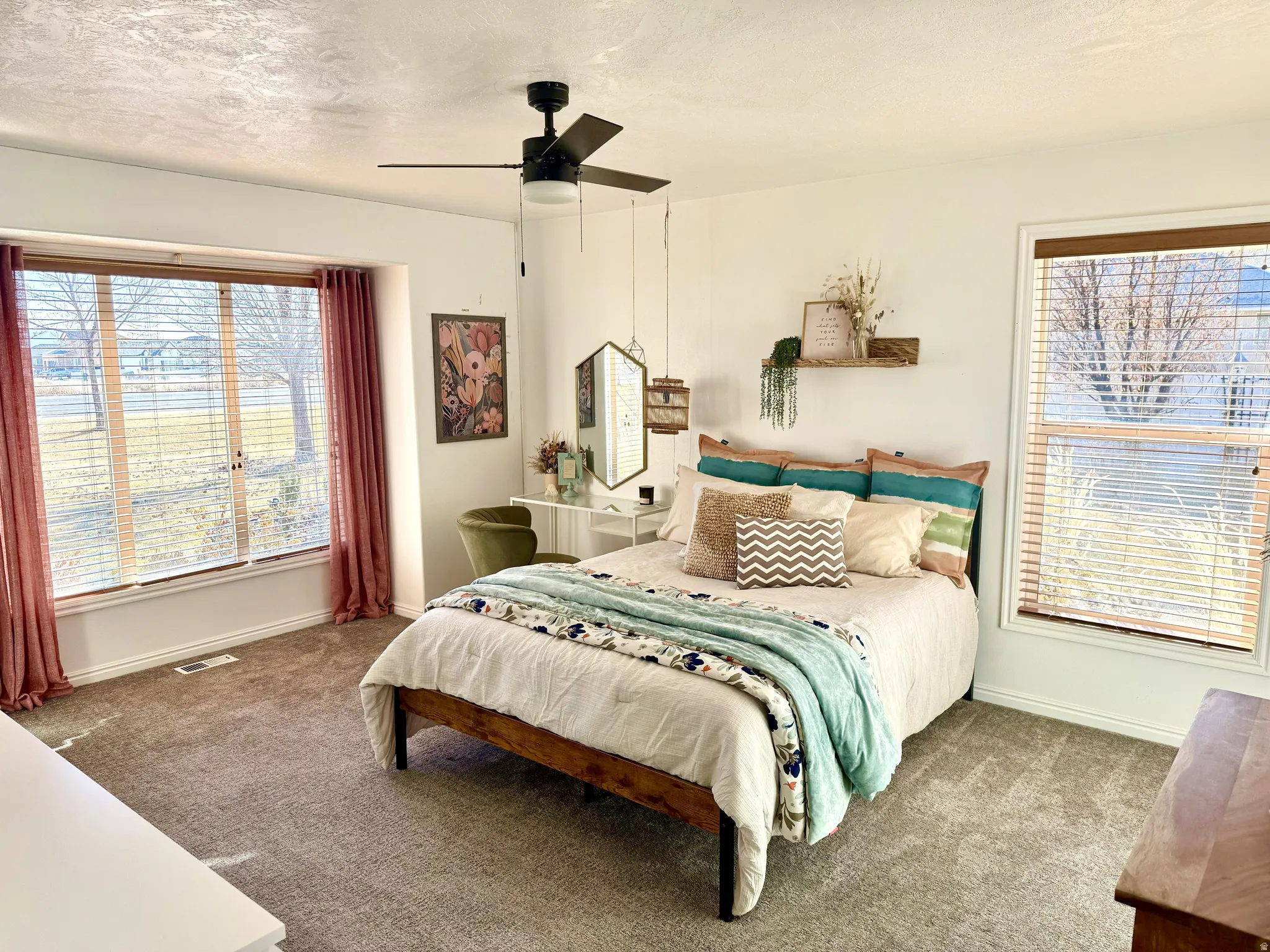 Carpeted room featuring a large bay window, a standard window, a ceiling fan with light fixture, and white wall finishes