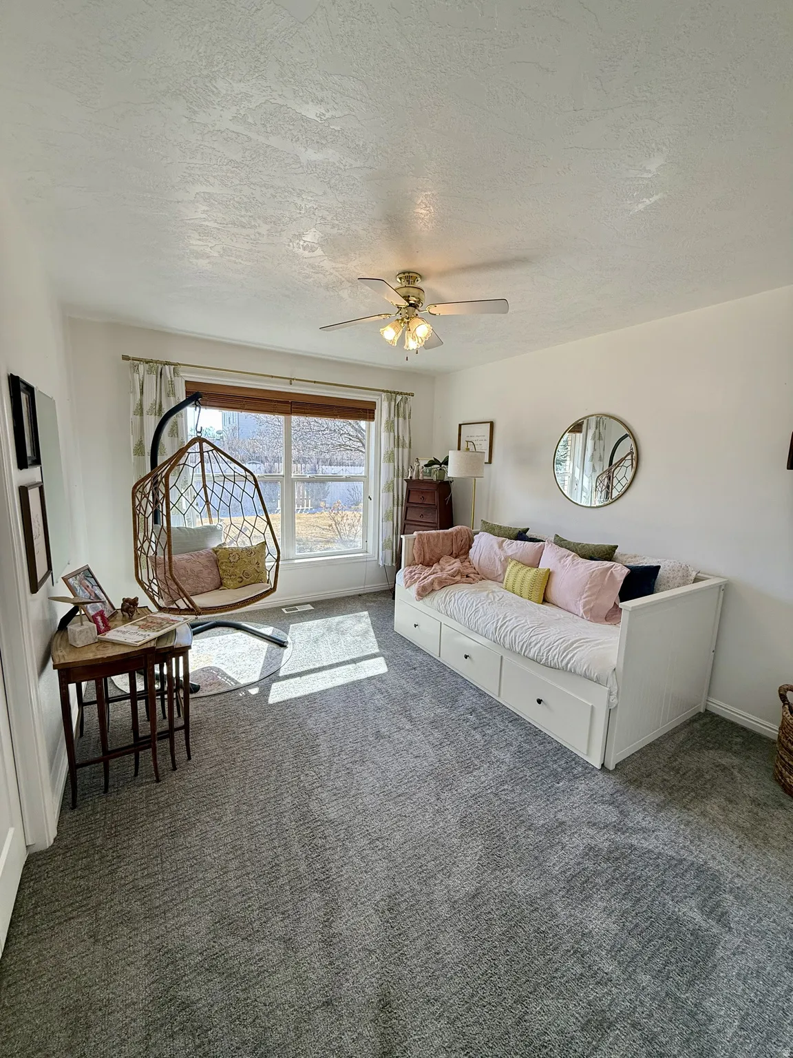 Carpeted room featuring a large window, a ceiling fan with integrated lighting, and white baseboards