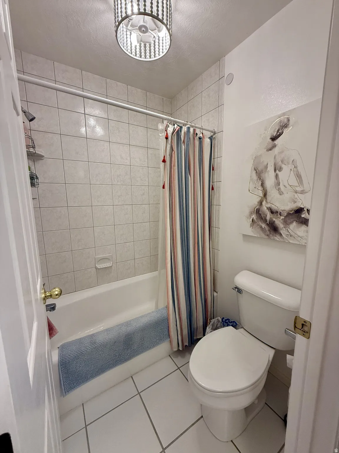 Full bathroom featuring a tub/shower combination with white tile surround, white floor tiling, and a flush-mounted ceiling light fixture