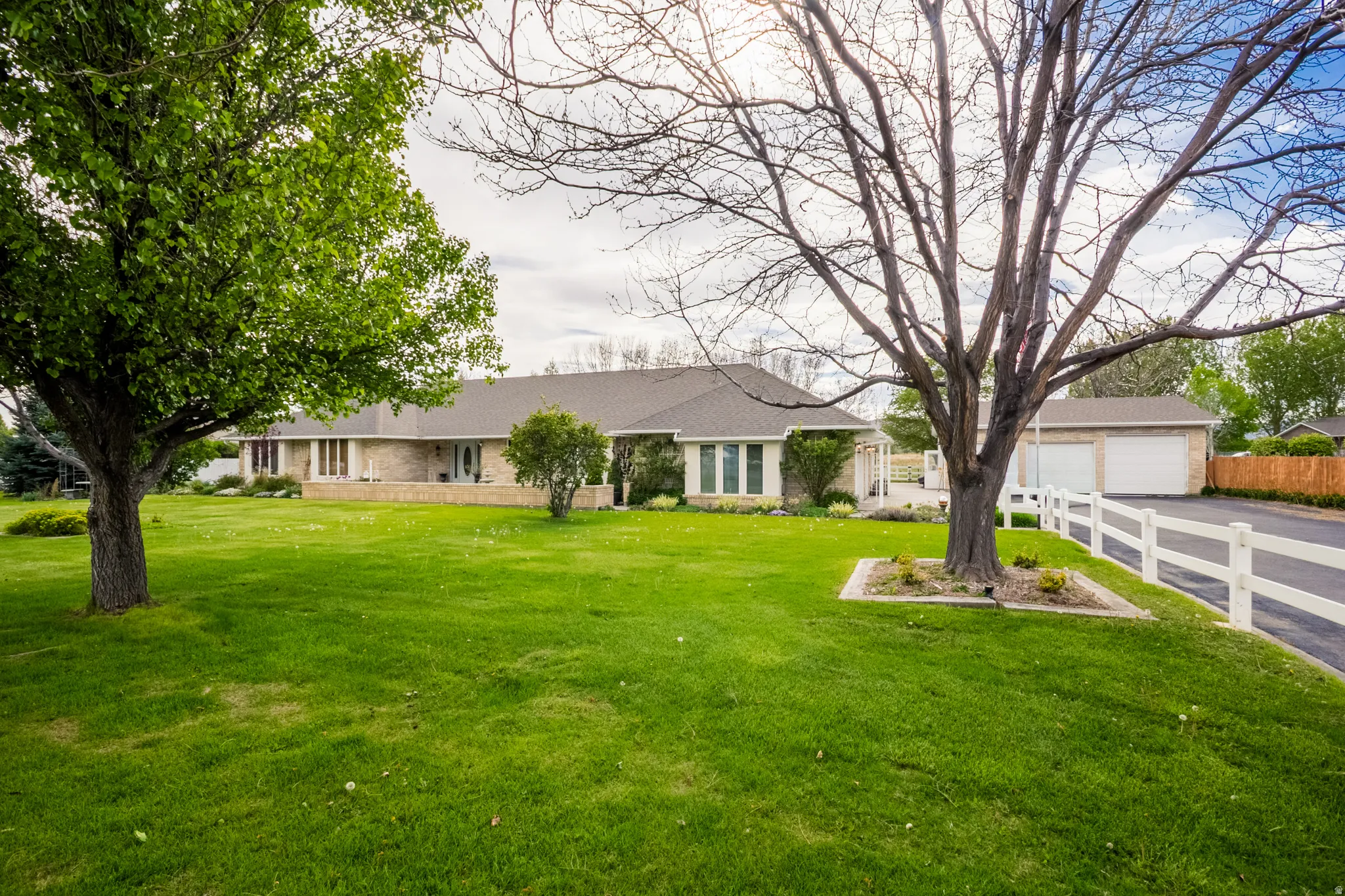 Expansive front lawn with mature trees and a manicured landscape