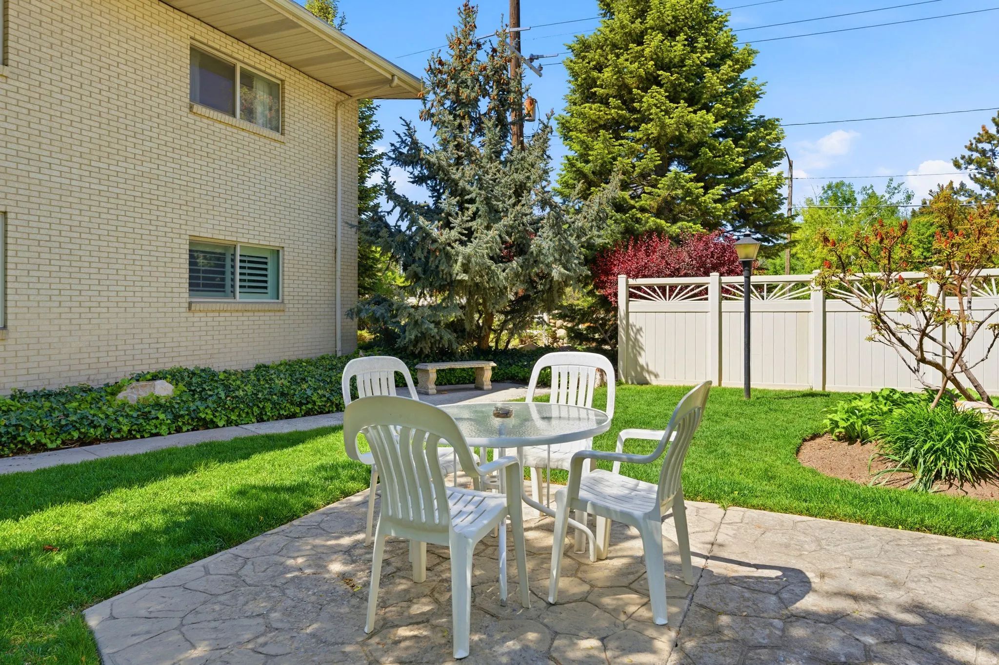 Expansive outdoor patio area featuring a stamped concrete surface, surrounding green lawn, and a privacy fence