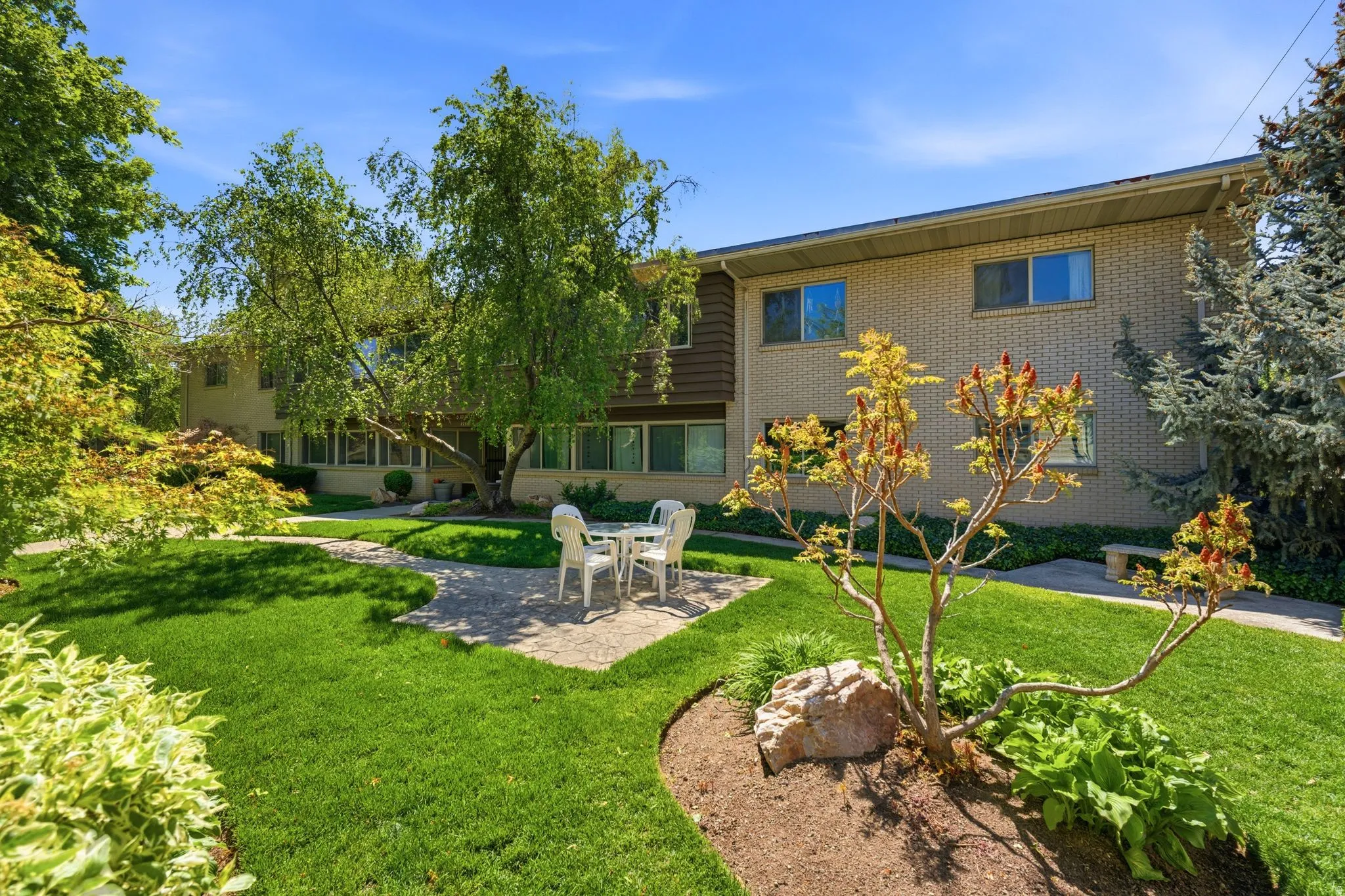 Expansive green lawn with mature trees and a paved patio area