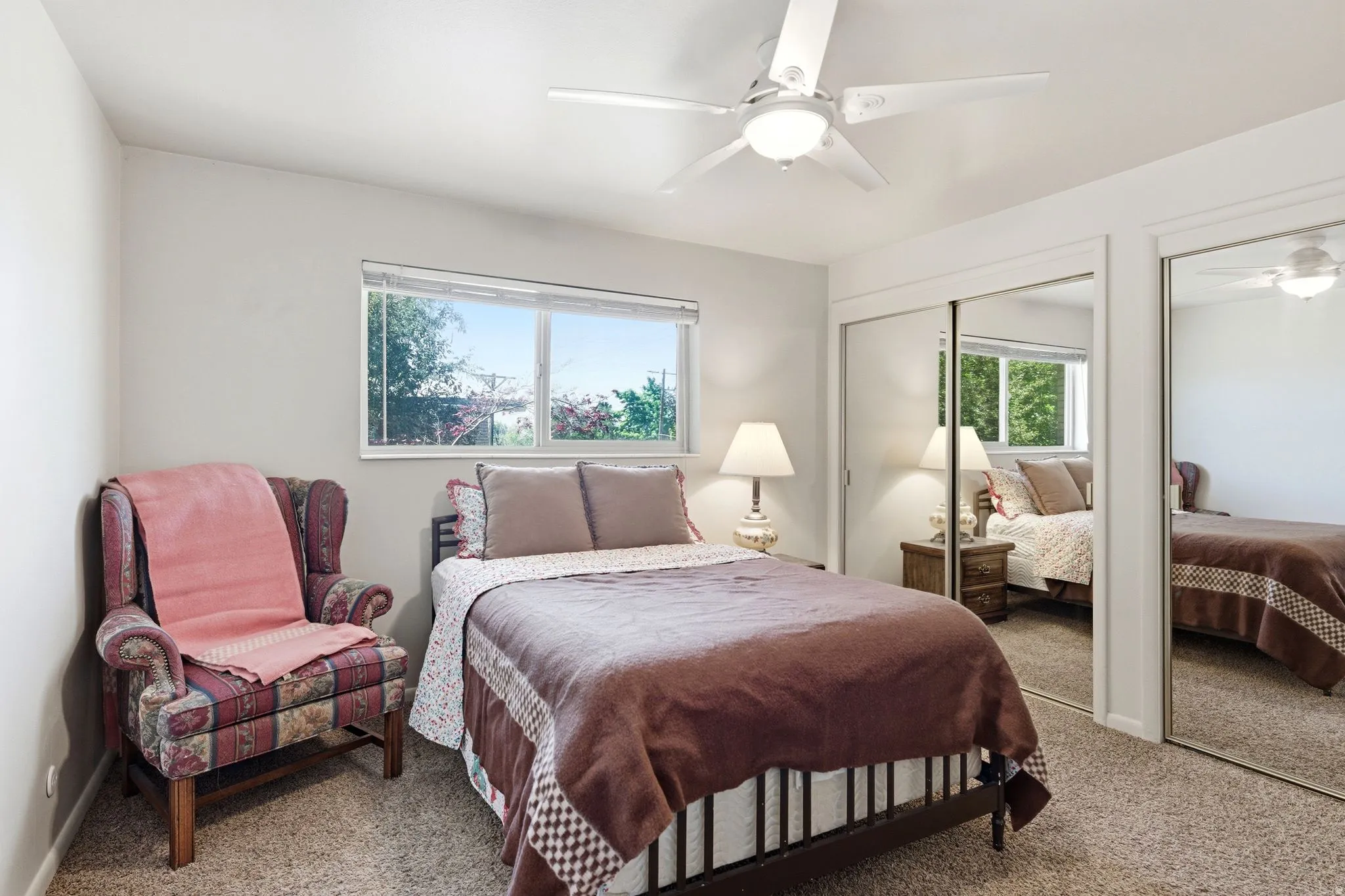 Bedroom featuring light-colored walls, a window with natural light, and two mirrored sliding closet doors