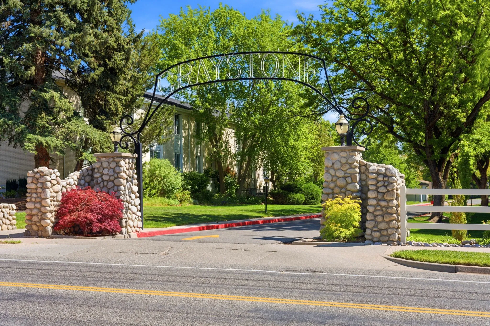 Stone pillar entrance featuring an ornamental wrought iron archway