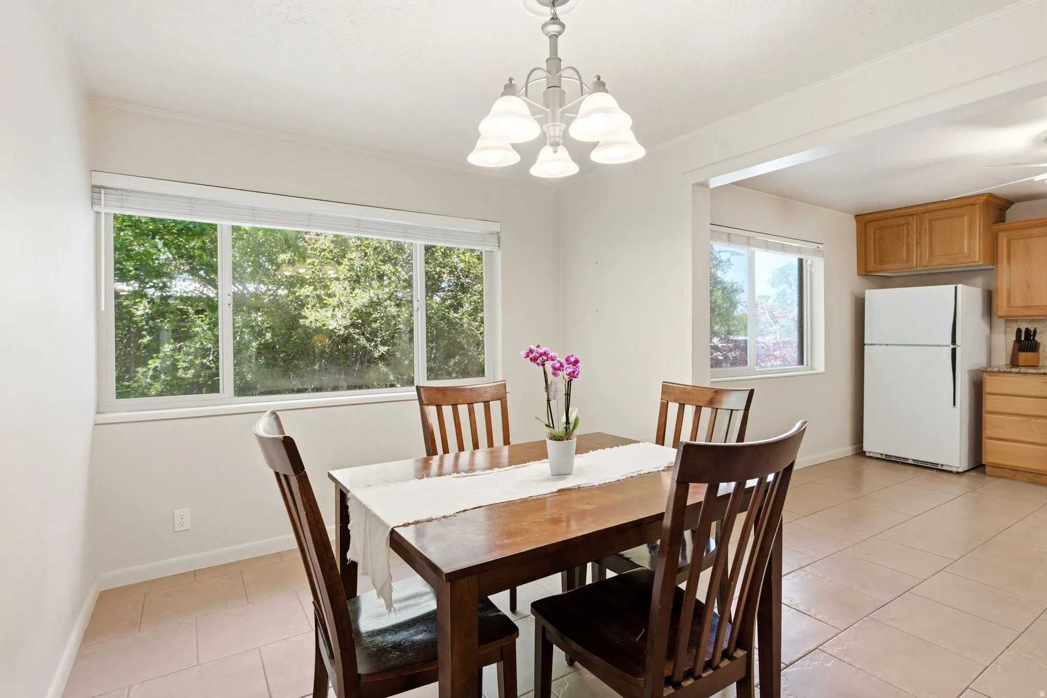 Dining area featuring a contemporary chandelier, large windows, and tile flooring