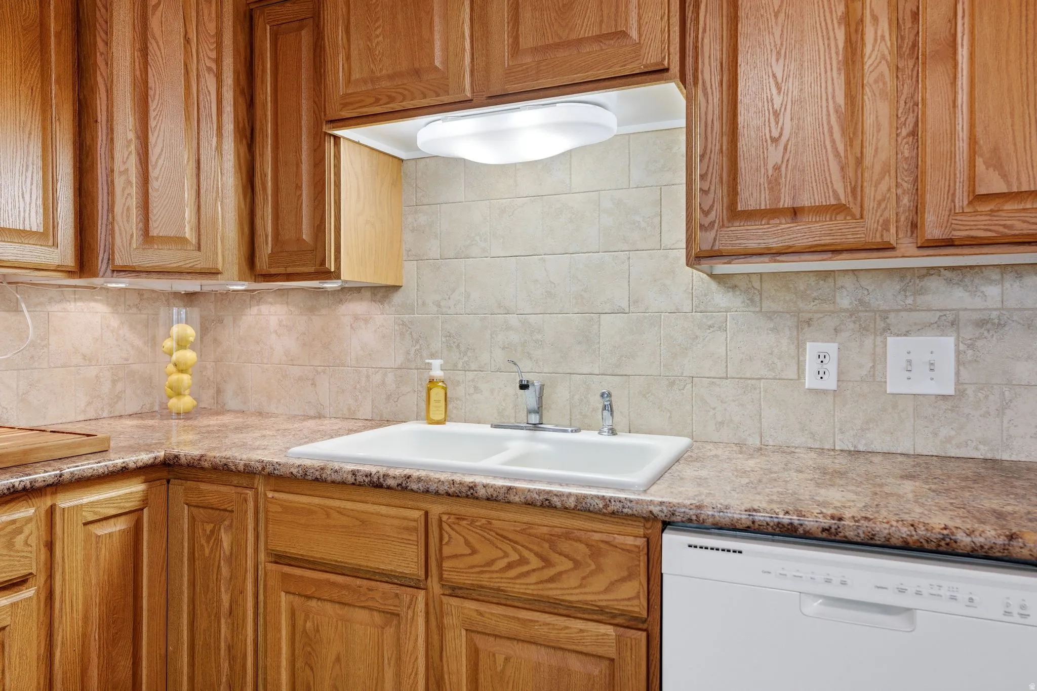 Kitchen area featuring wood cabinetry and a double basin sink