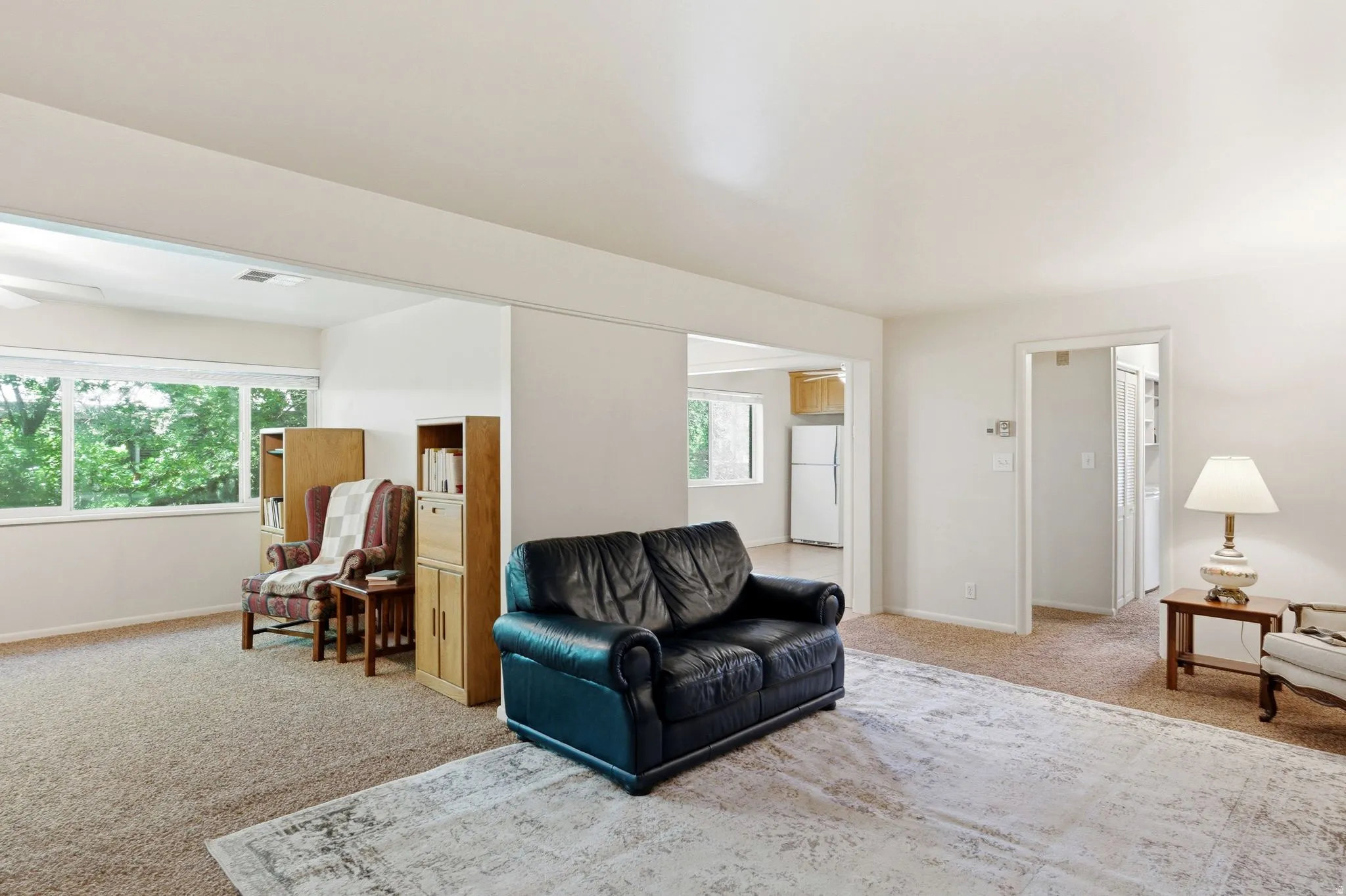 Carpeted living space featuring an expansive window, built-in shelving, and an open doorway to an additional room