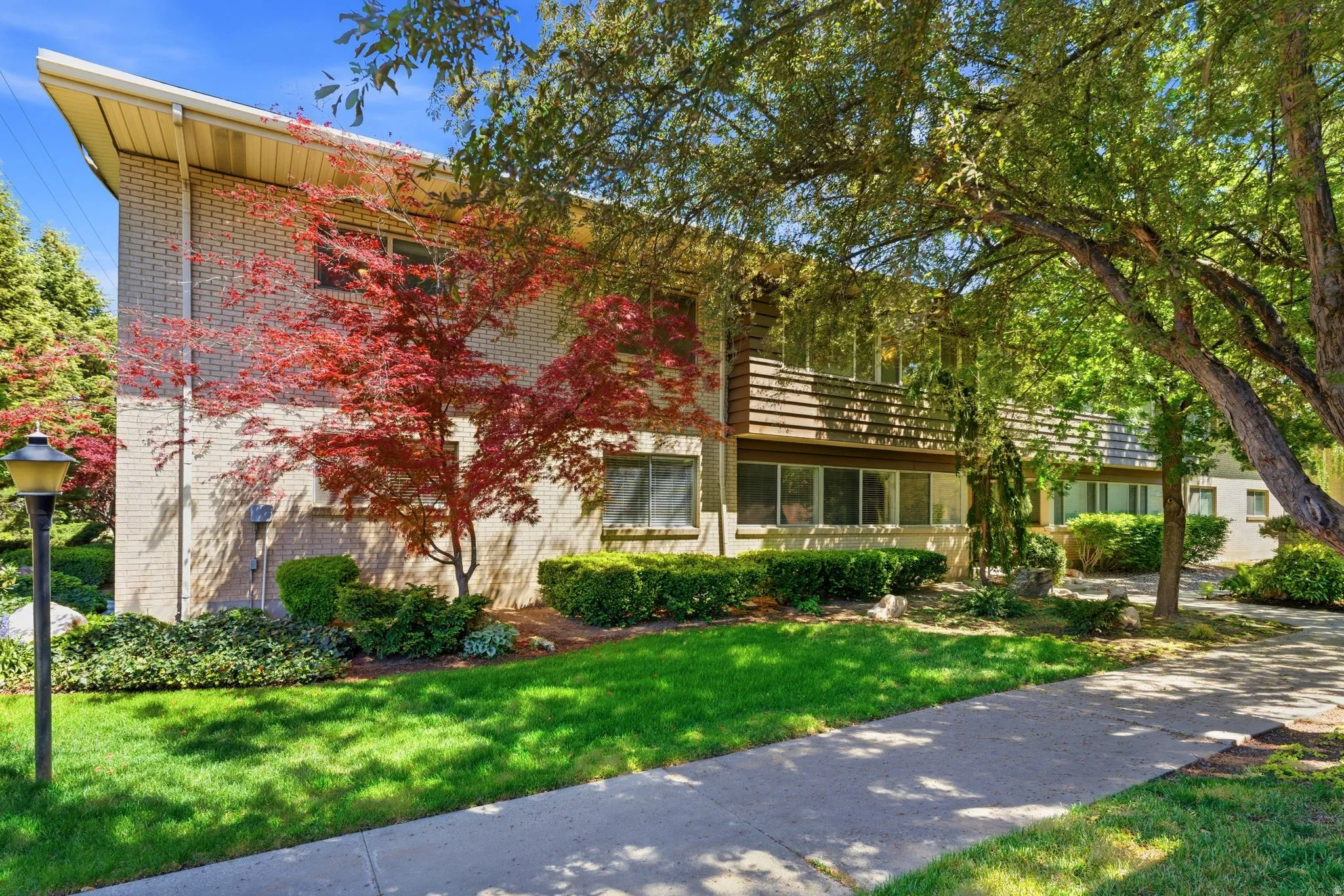 Brick and wood-sided exterior featuring mature trees and established landscaping