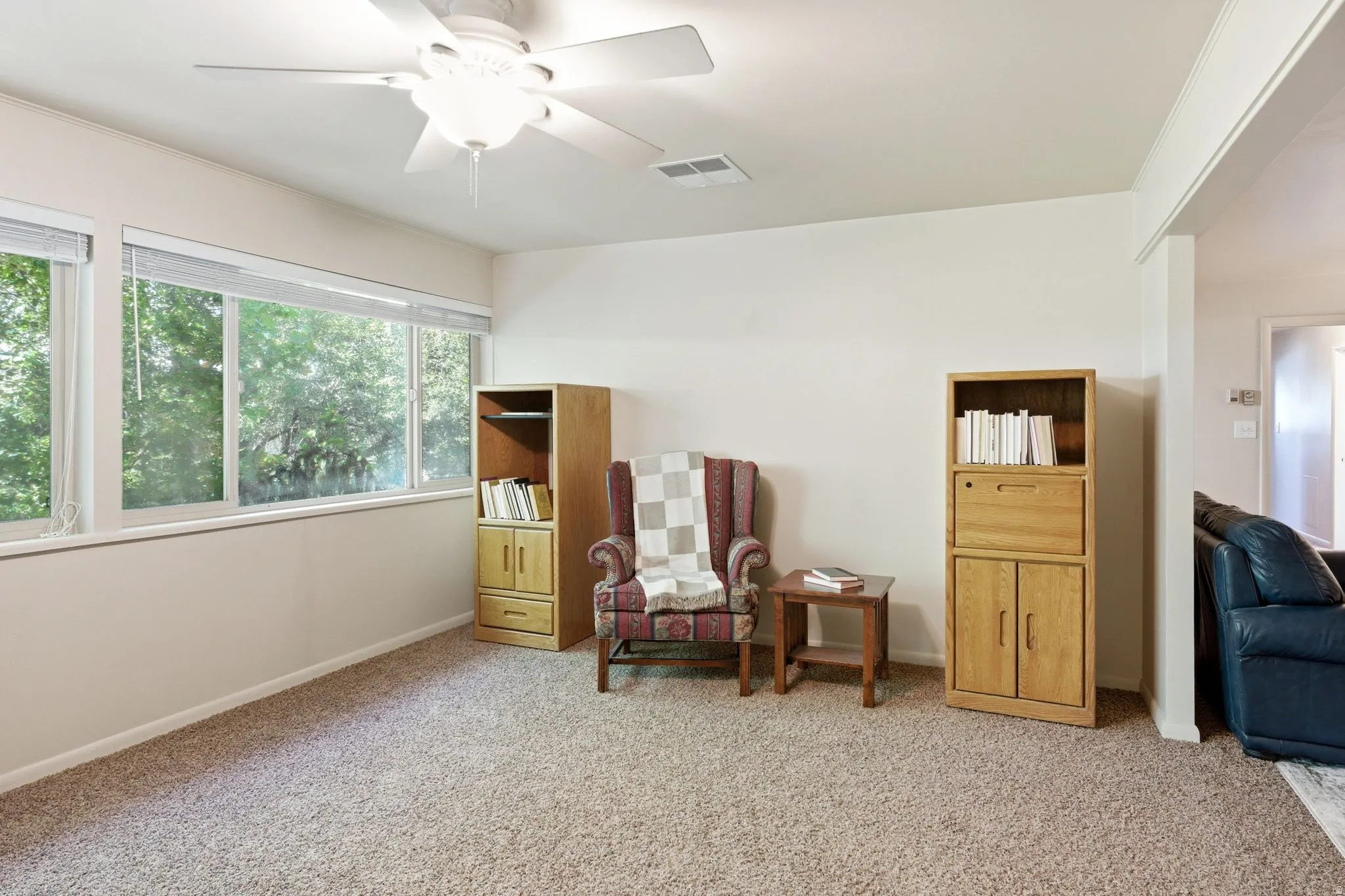 Wall-to-wall carpeting with multiple windows, a ceiling fan, and built-in shelving units