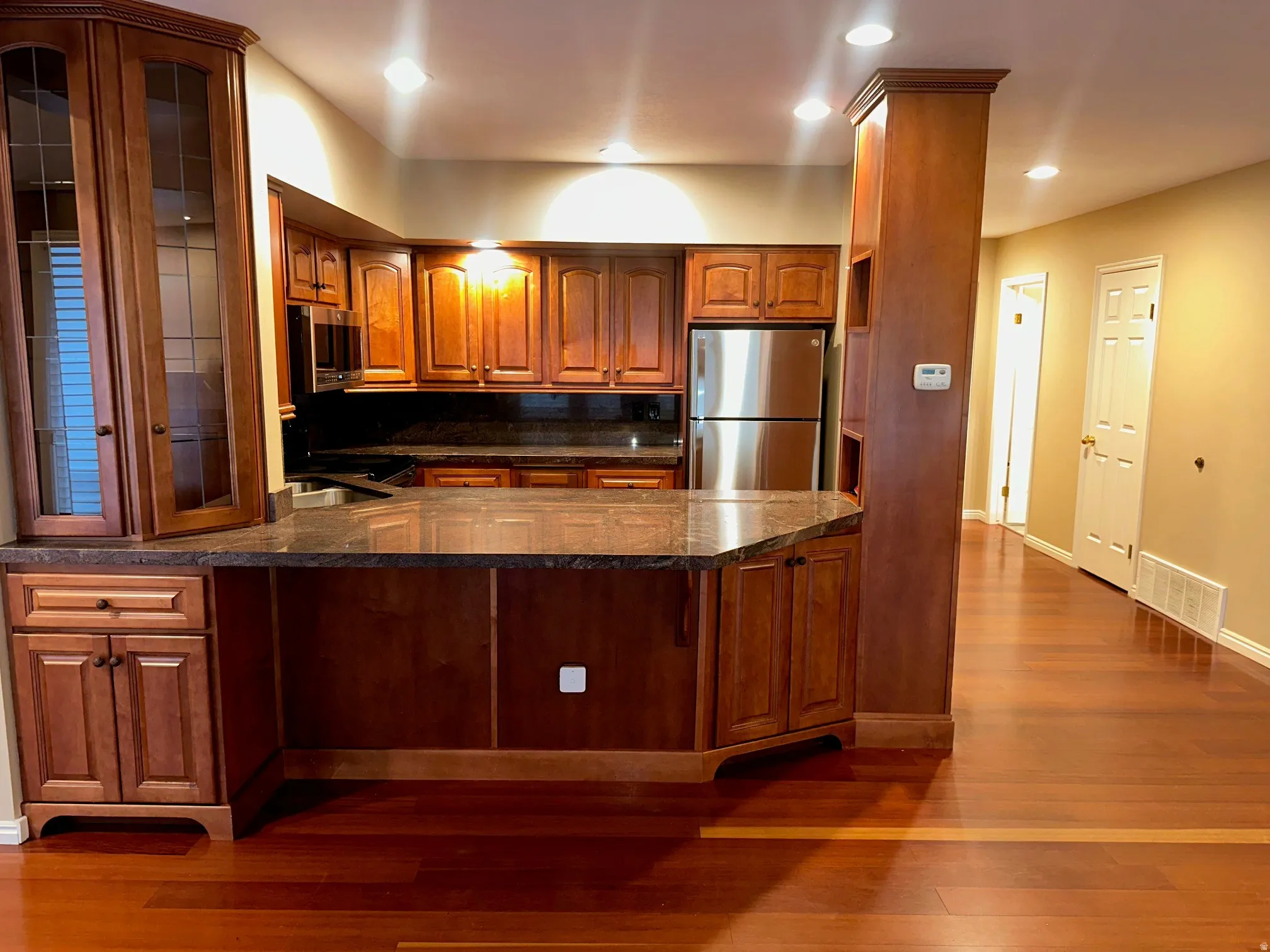Kitchen featuring wood cabinetry, dark countertops, recessed lighting, and stainless steel appliances