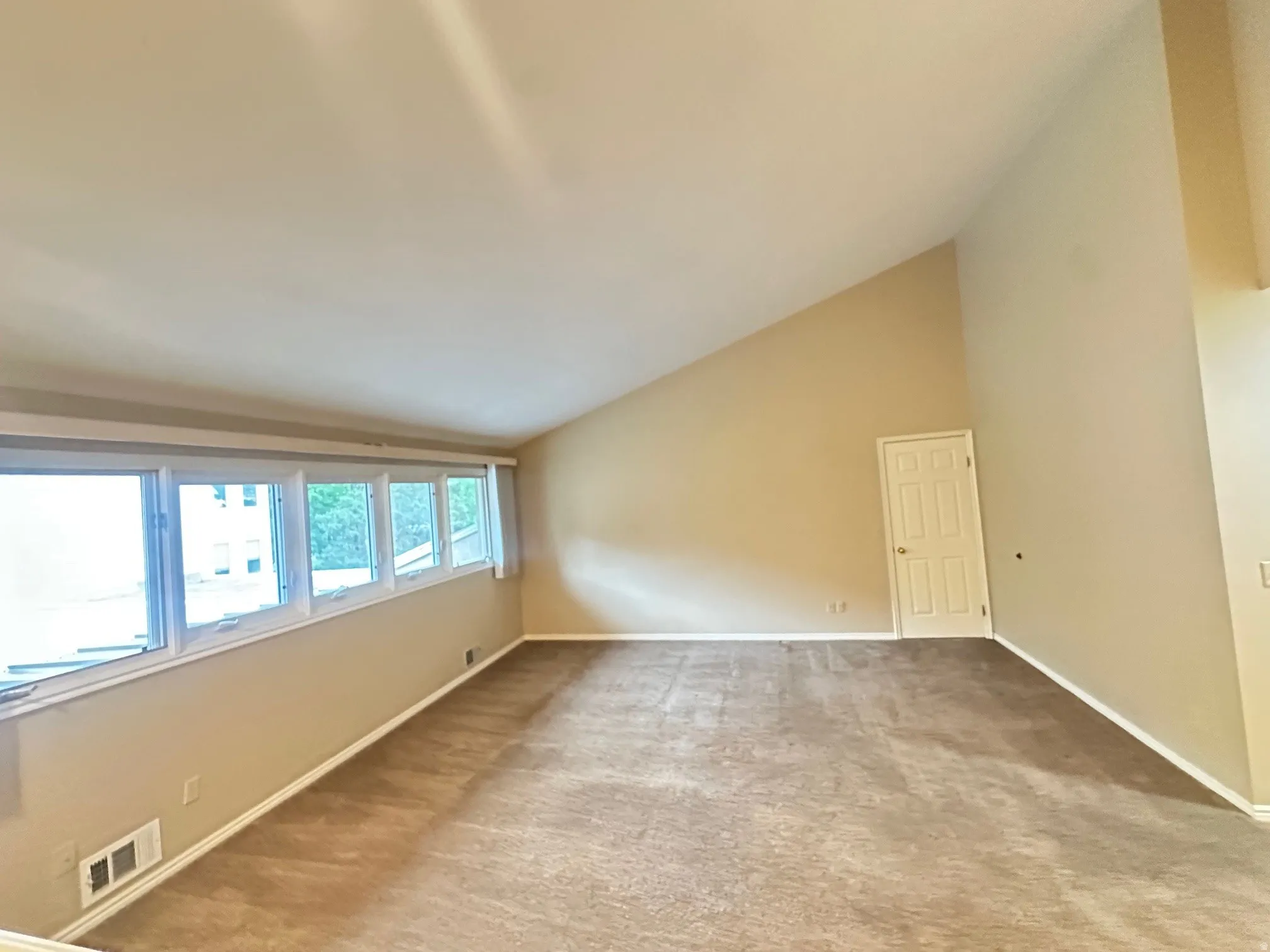 Spacious room featuring vaulted ceilings and natural light from large windows