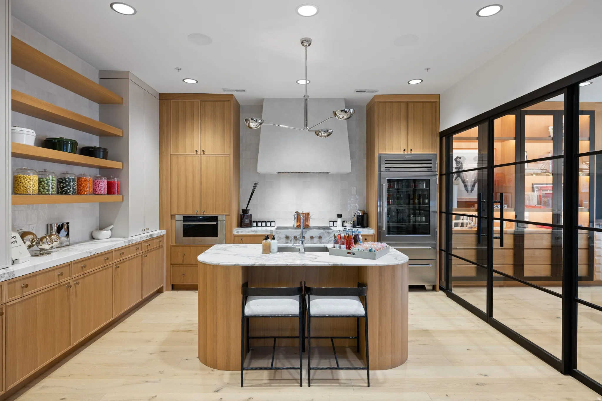 Modern kitchen featuring light wood-finish cabinetry, a central island with a white countertop, and integrated stainless steel appliances