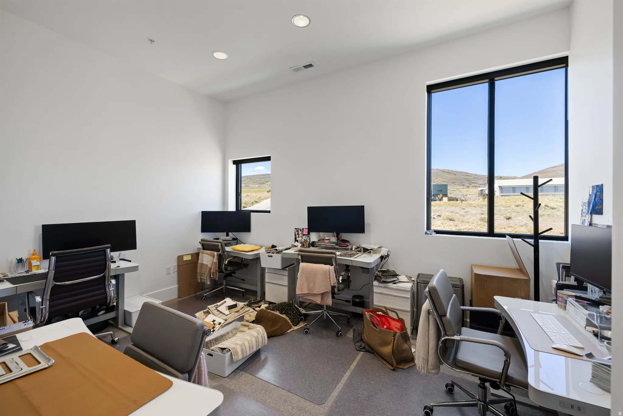 High ceilings and recessed lighting illuminate this bright space, featuring multiple large windows with black frames