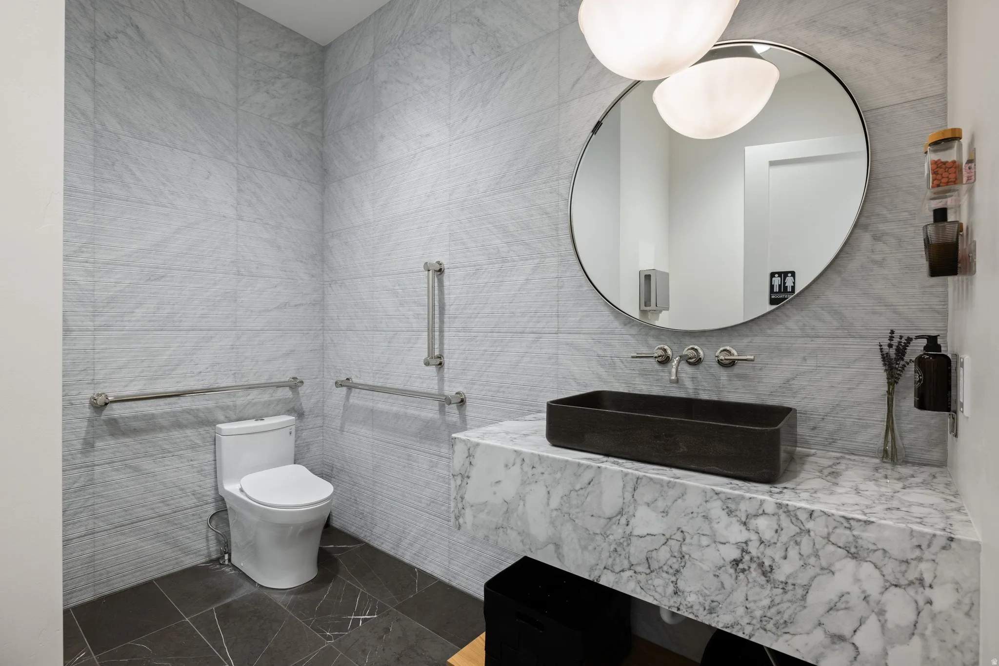 Modern washroom featuring full-height light marble-patterned wall tiles and dark floor tiles