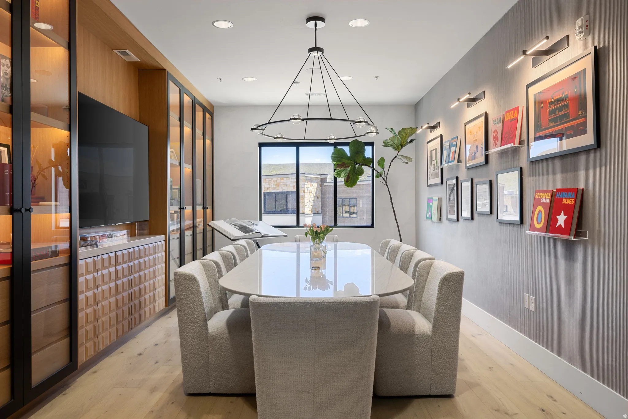 Dining area featuring wood-finish flooring, a contemporary chandelier, and a large window