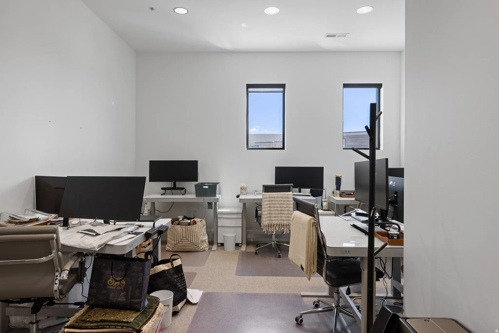 Office space featuring recessed lighting, a neutral color palette, and two windows with black trim