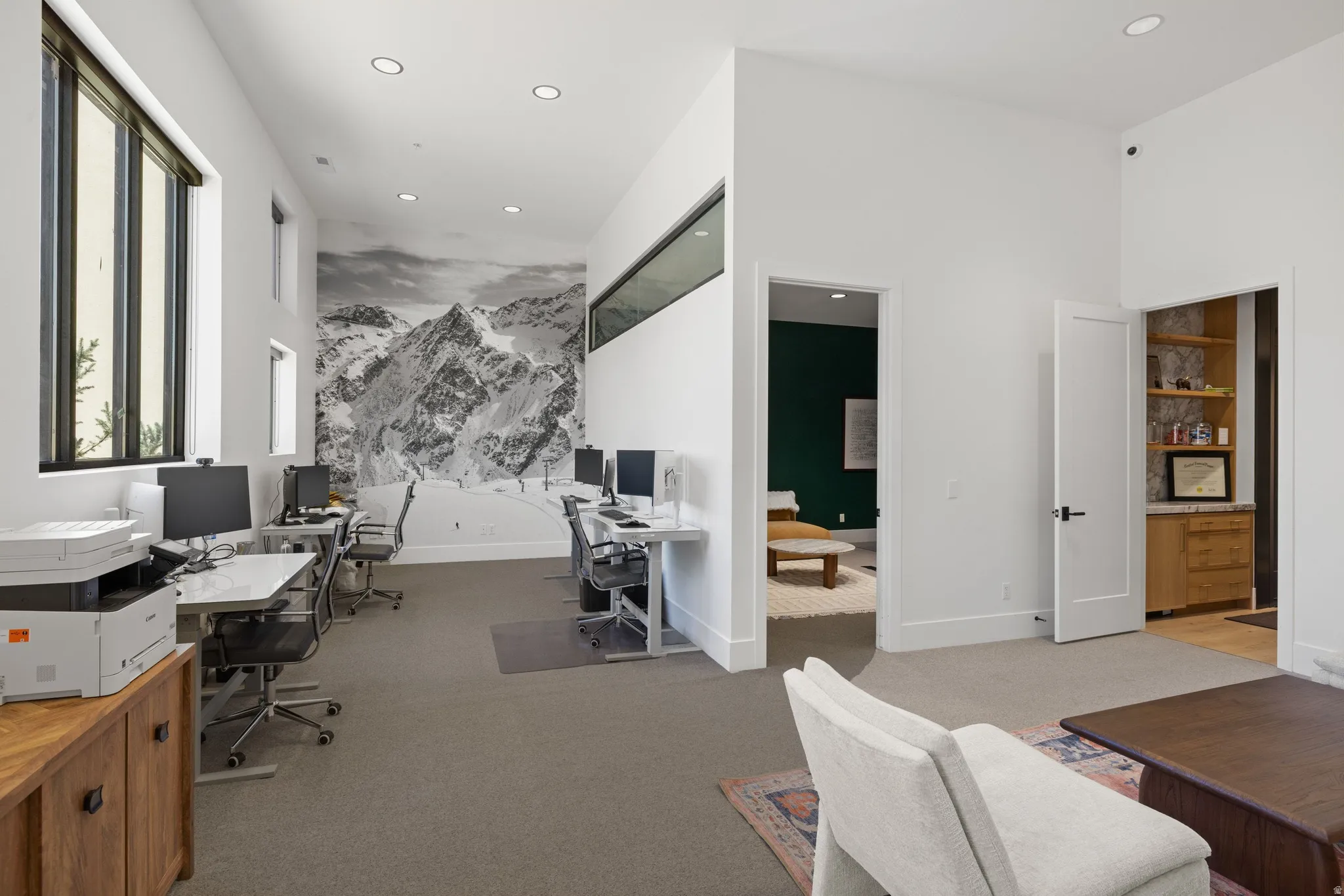 Spacious room featuring a mountain-themed accent wall, recessed lighting, and high ceilings