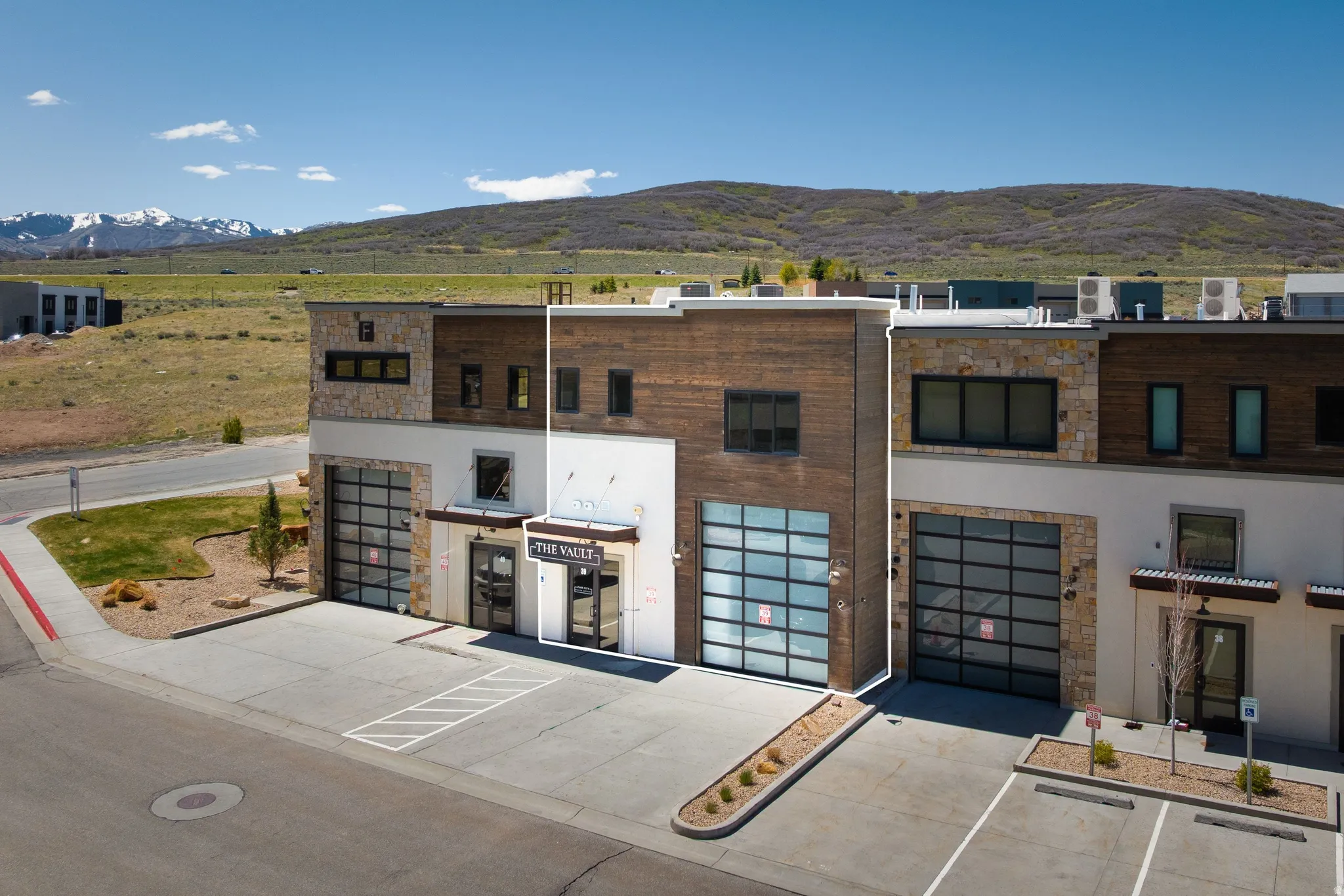 Modern commercial building featuring a mixed-material facade with stone, wood-finish siding, and white stucco
