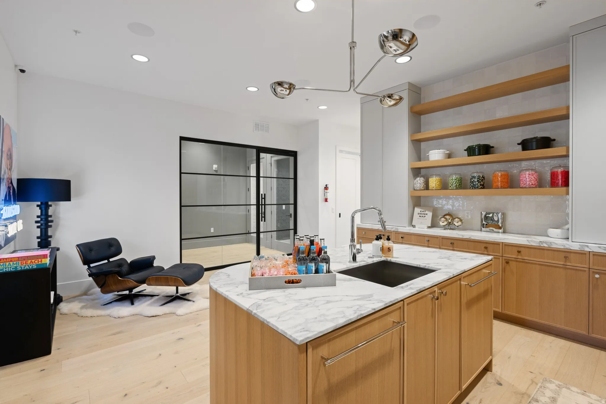Kitchen island with a white marble countertop and integrated sink, complemented by light wood-finish cabinetry