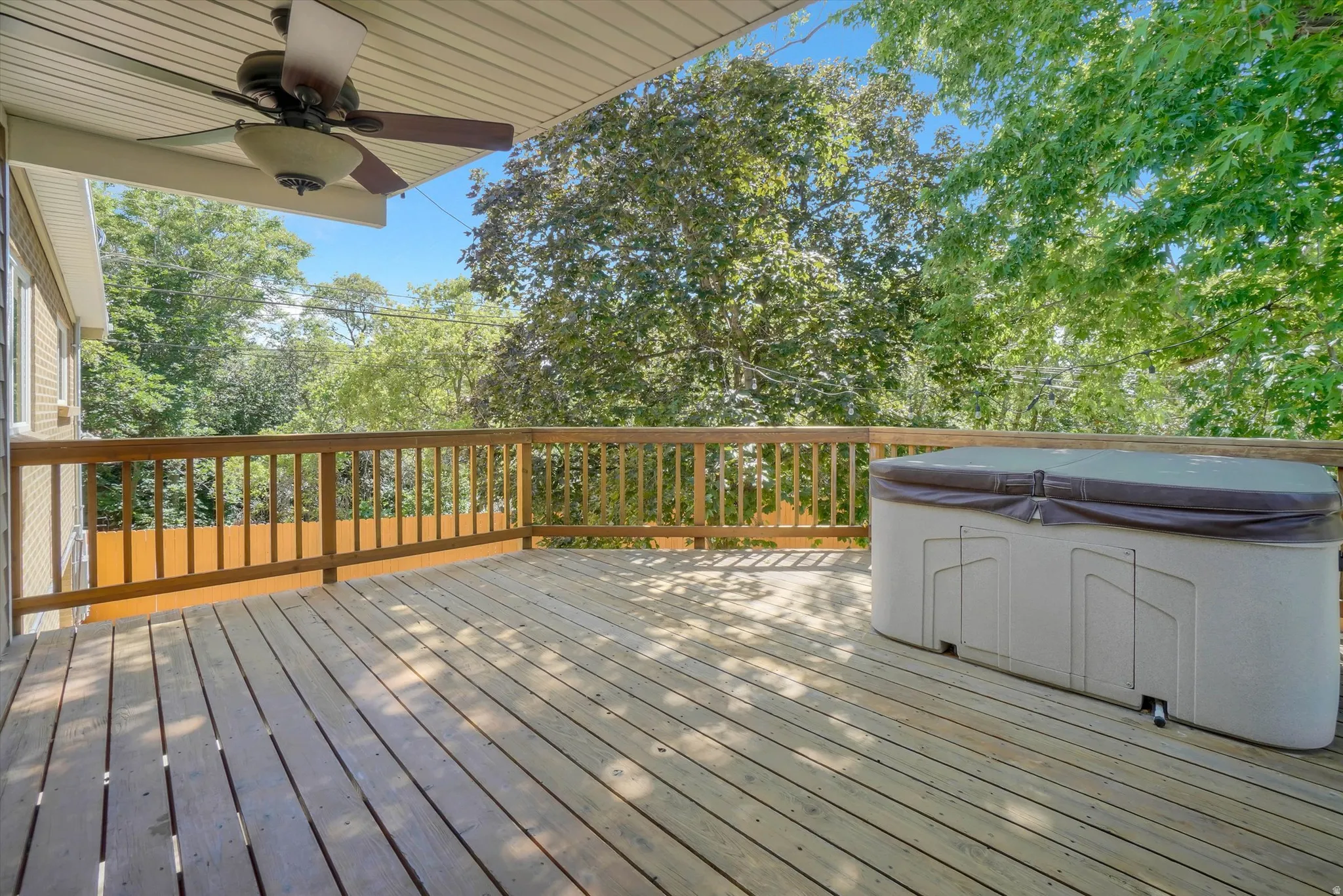 Spacious outdoor deck featuring natural wood flooring and a built-in outdoor spa