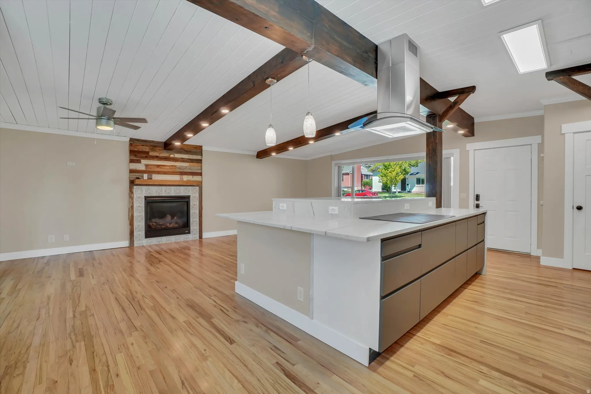 Open-concept living space with vaulted ceilings, exposed wood beams, and natural wood-finish flooring