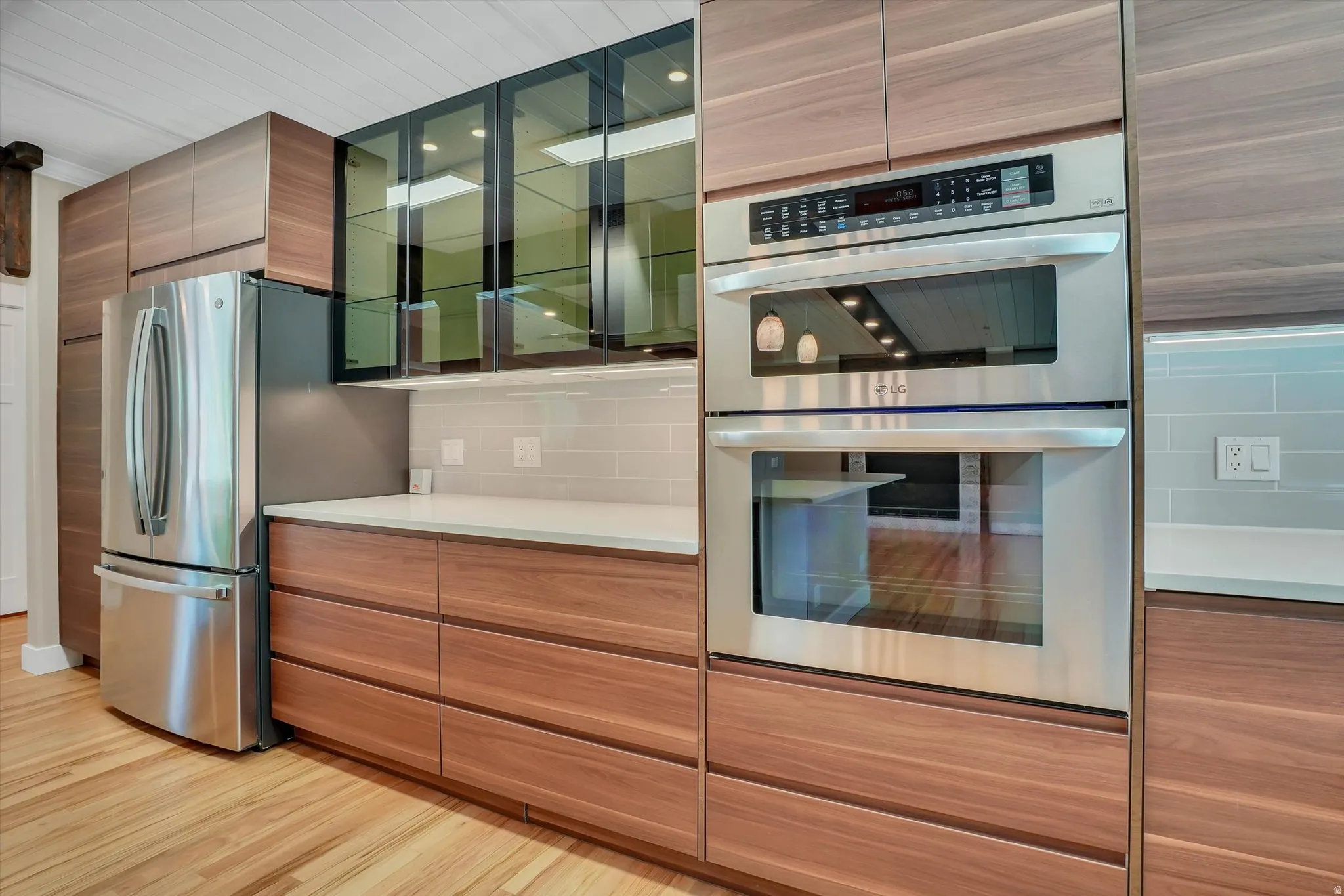 Modern kitchen featuring stainless steel appliances, wood-finish cabinetry, and light quartz countertops