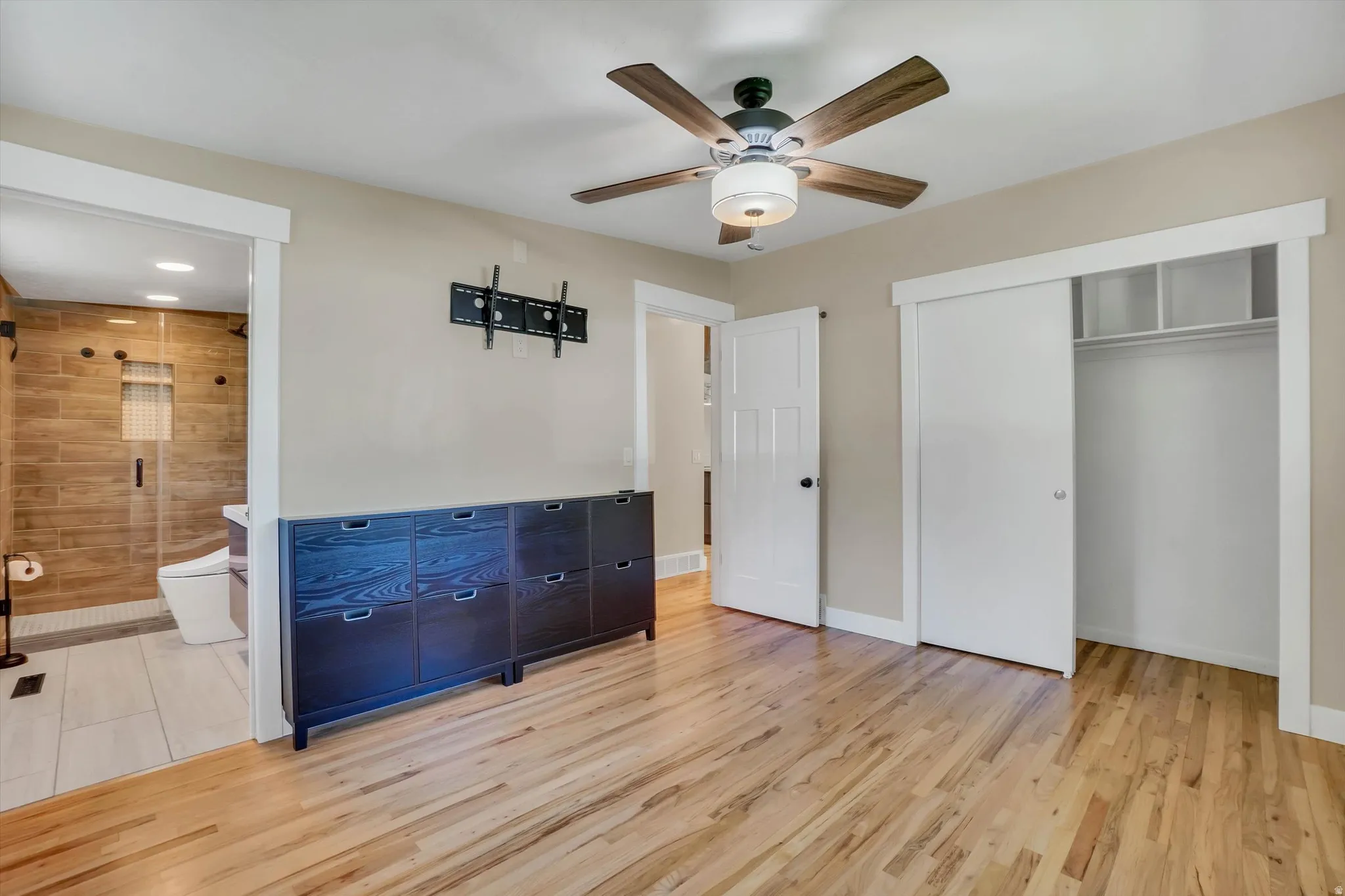 Bedroom with hardwood flooring and a ceiling fan with integrated lighting