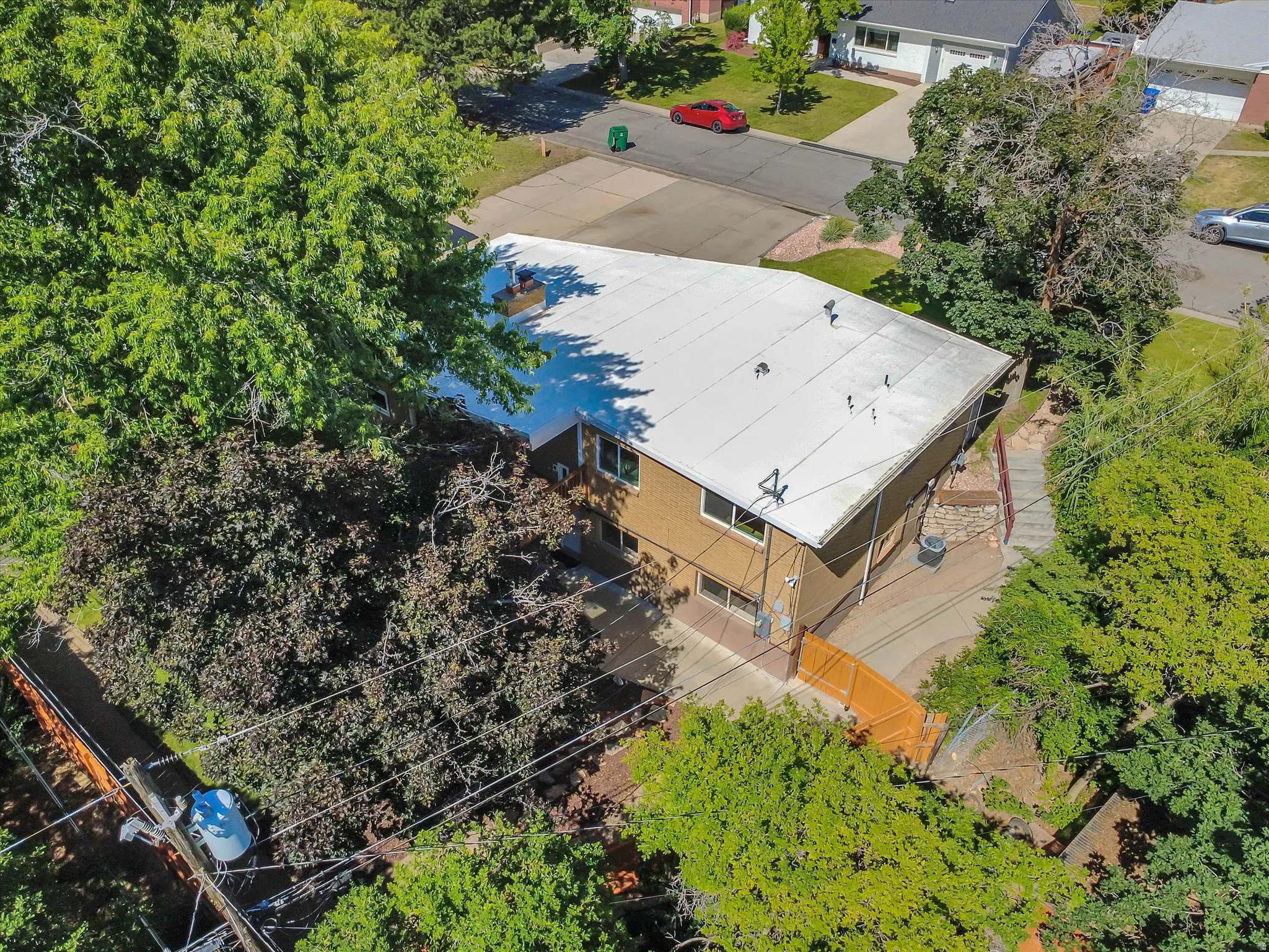 Aerial perspective showcasing a light-colored roof, surrounded by mature trees