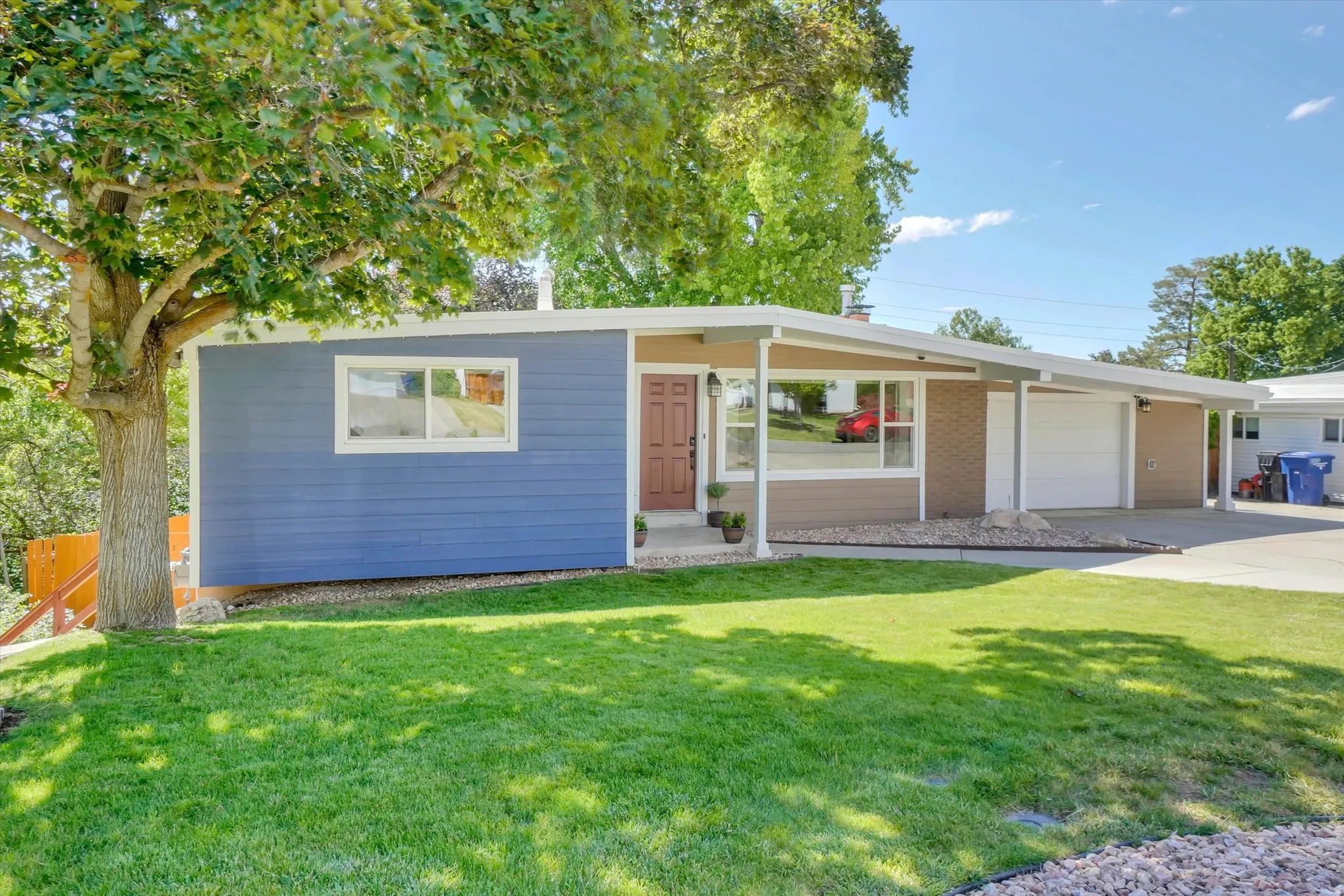 Ranch-style exterior featuring blue siding, a covered entry, and an attached two-car garage