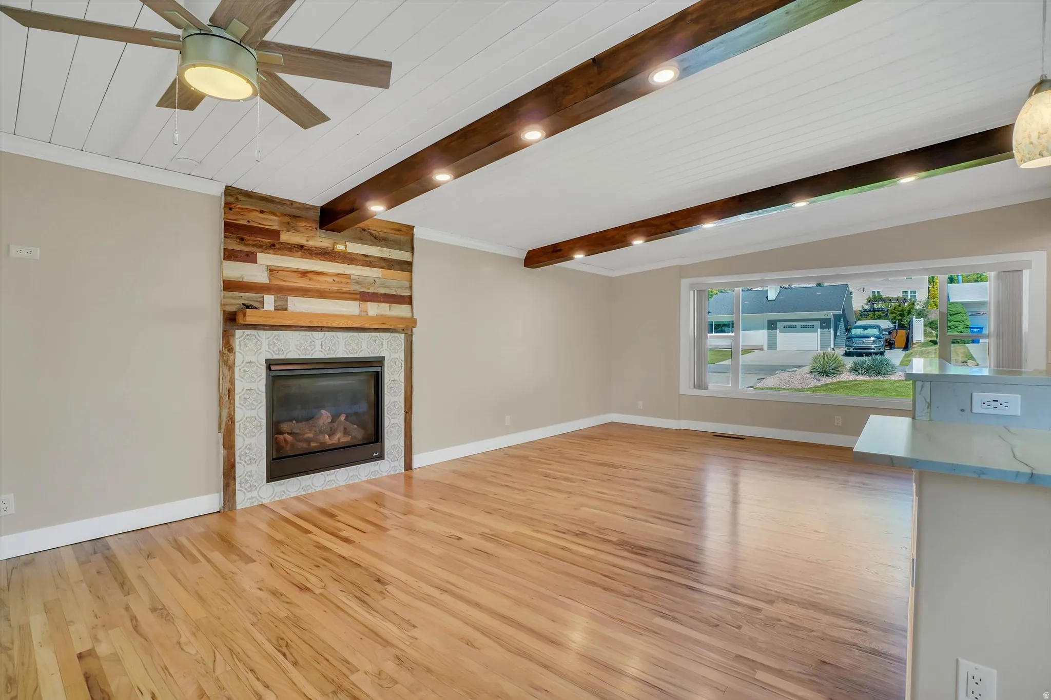 Living space featuring a wood-panel accent wall with a fireplace, hardwood flooring, and a decorative ceiling fan