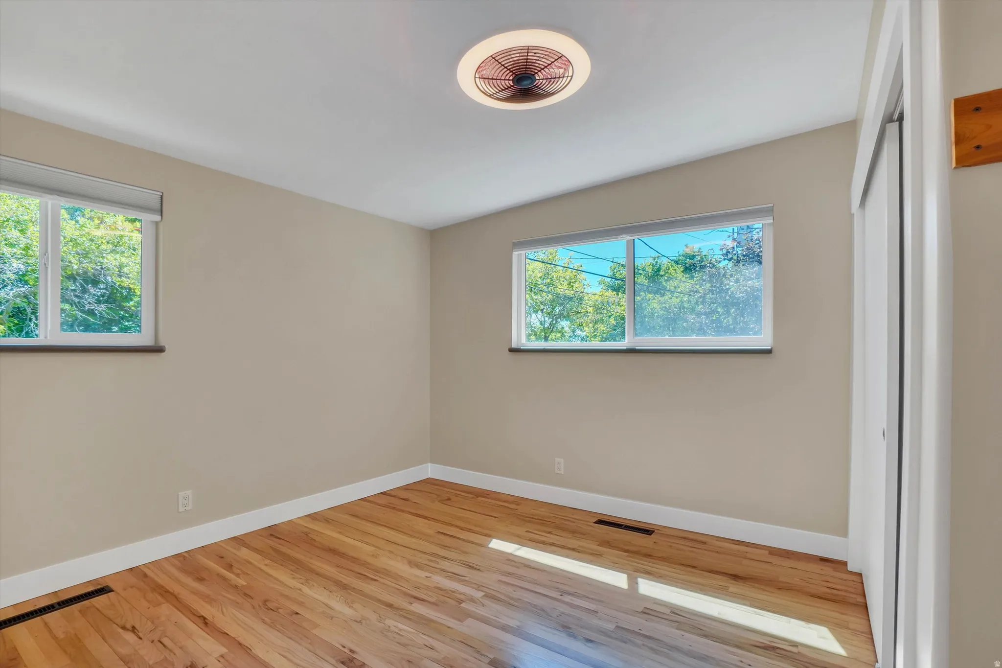 Spacious room featuring wood-finish flooring, light-toned walls, and white trim