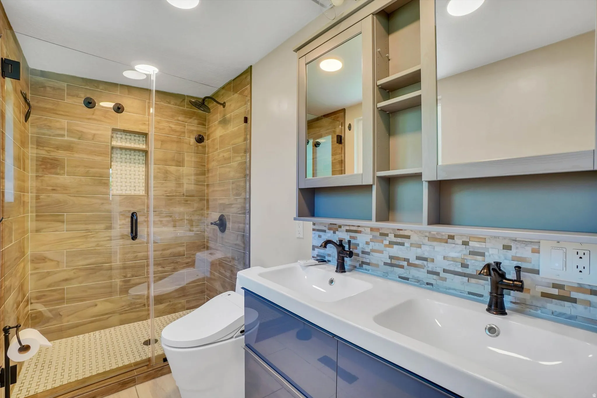 Full glass shower enclosure with wood-finish tile surround and a tiled shower pan