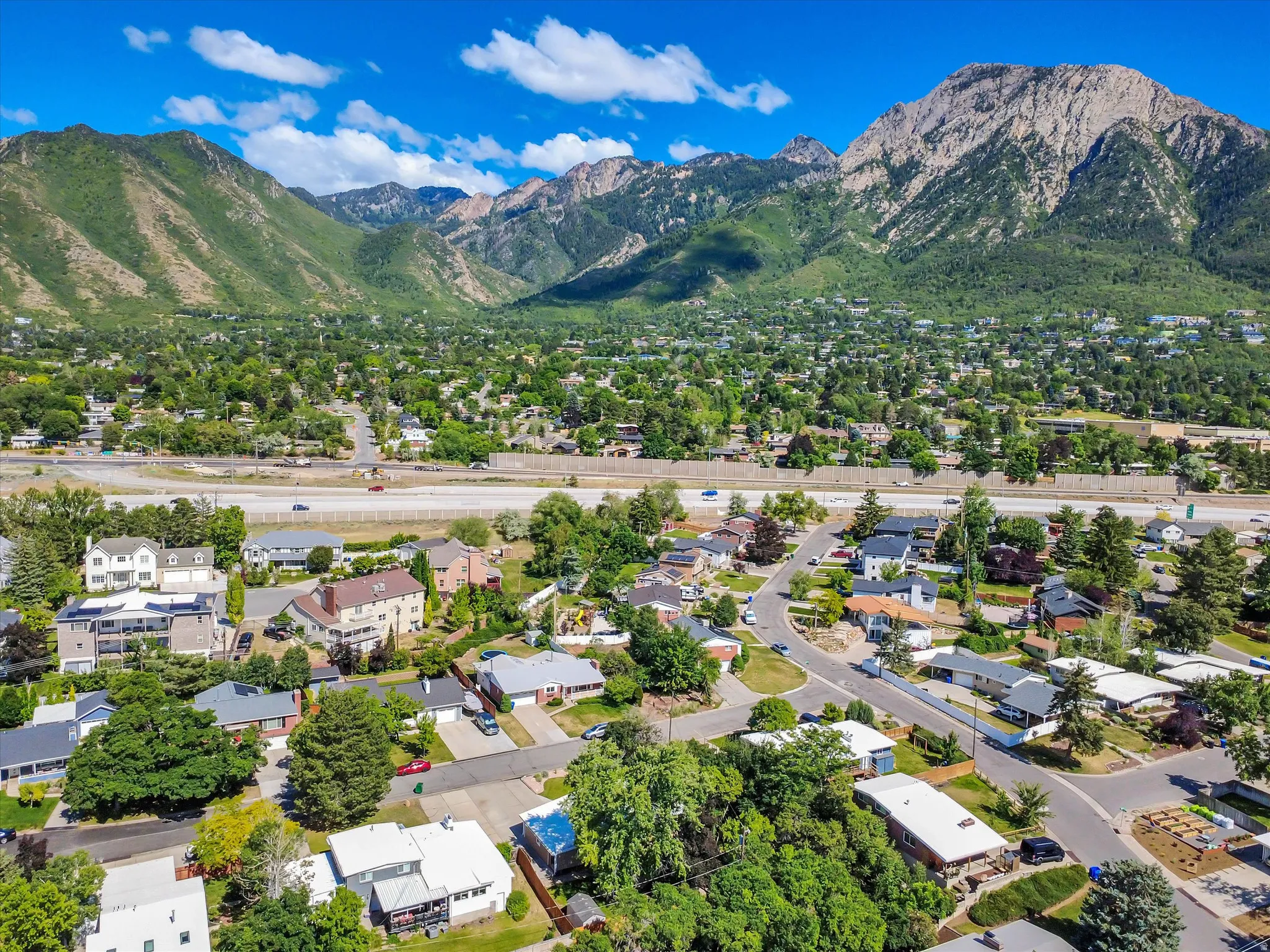 Expansive mountain range backdrop framing a residential area with diverse architecture and mature tree coverage