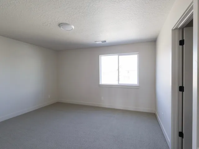 Carpeted flooring, white walls, white trim, recessed lighting, and a window with white framing