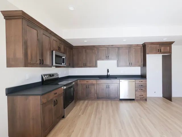L-shaped kitchen with wood-finish cabinetry, dark countertops, and stainless steel appliances