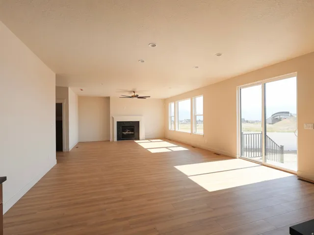 Spacious living area featuring wood-finish flooring, a fireplace with a mantel, recessed lighting, and a ceiling fan