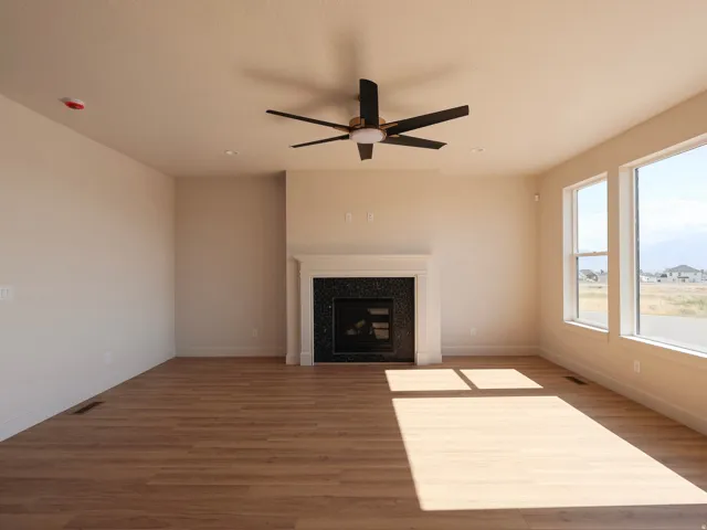 Spacious room featuring wood-finish flooring, a contemporary ceiling fan, and a fireplace with a dark tiled surround and white mantel