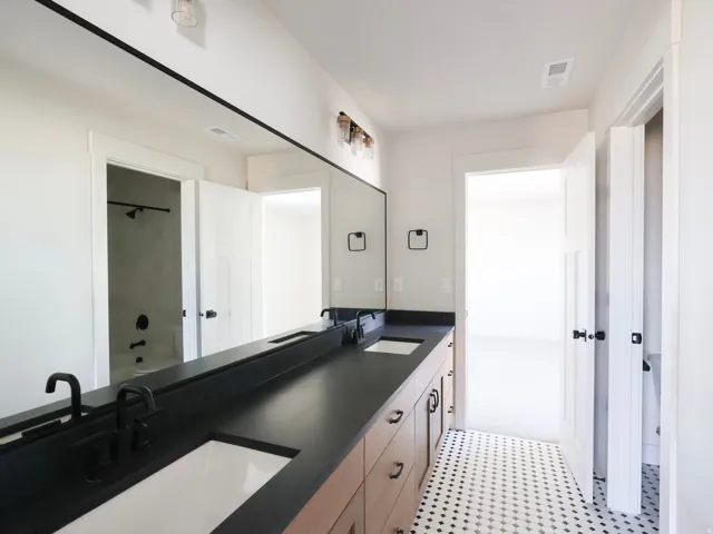 Dual vanity with integrated sinks, dark countertop, and matte black fixturesJack and Jill bathroom