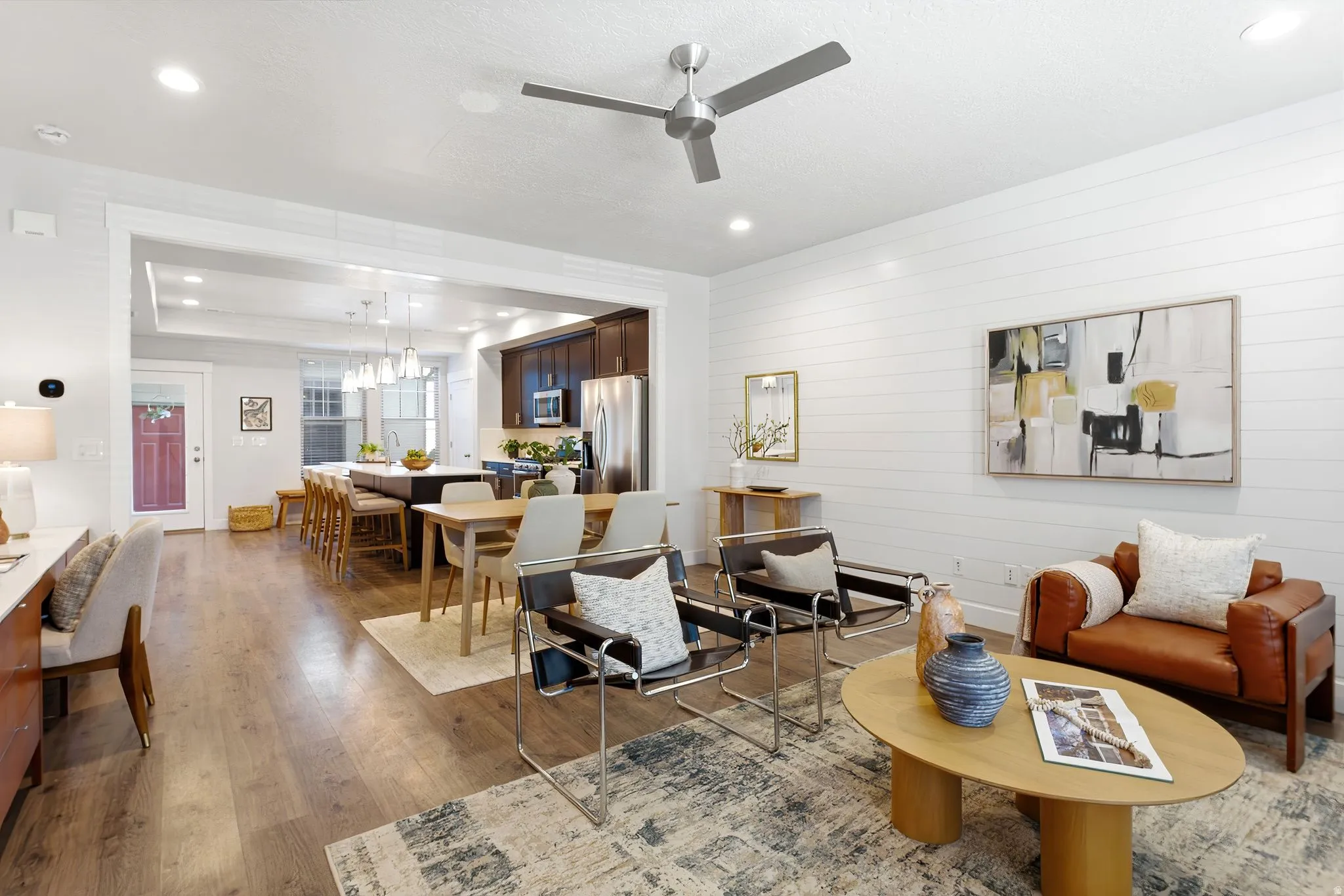 Open-concept living area featuring wood-finish flooring, a contemporary ceiling fan, recessed lighting, and a shiplap accent wall