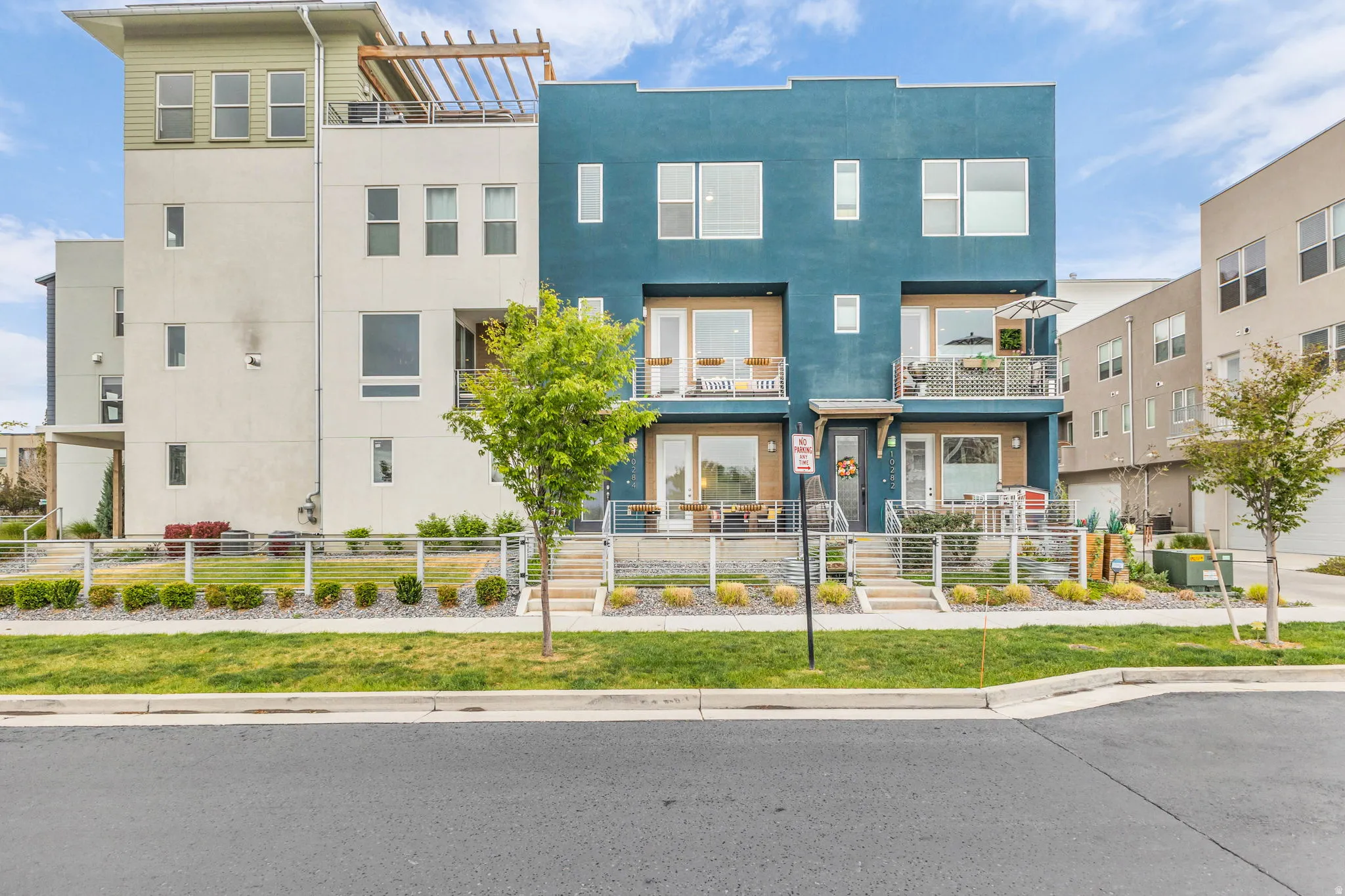 Contemporary townhome featuring a distinctive teal facade with wood-finish accents