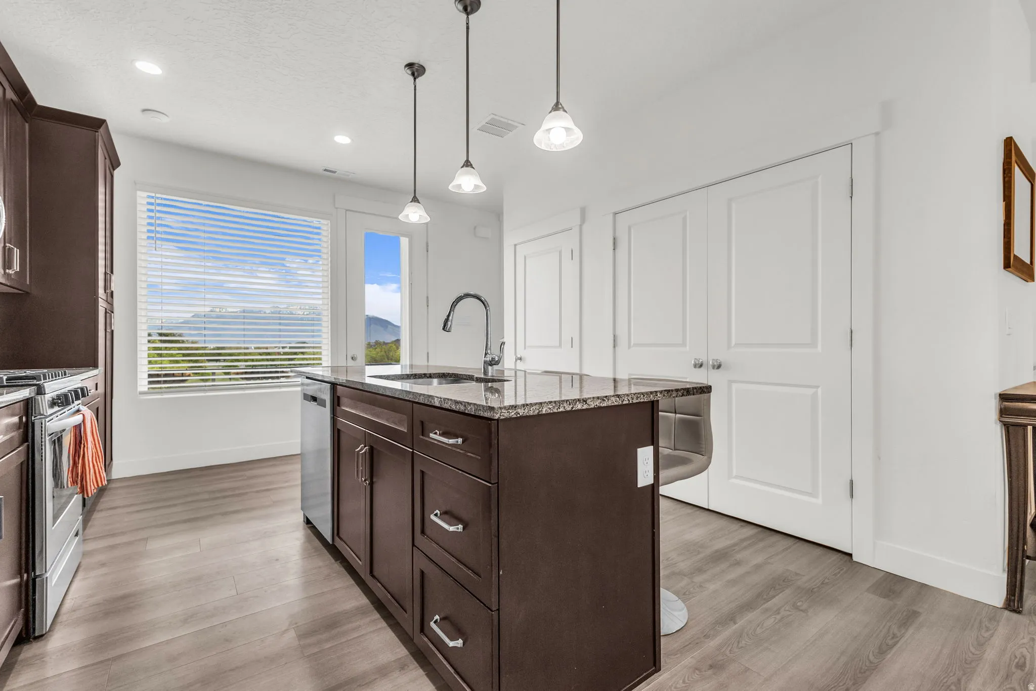 Kitchen island with granite countertop, integrated sink, and stainless steel dishwasher